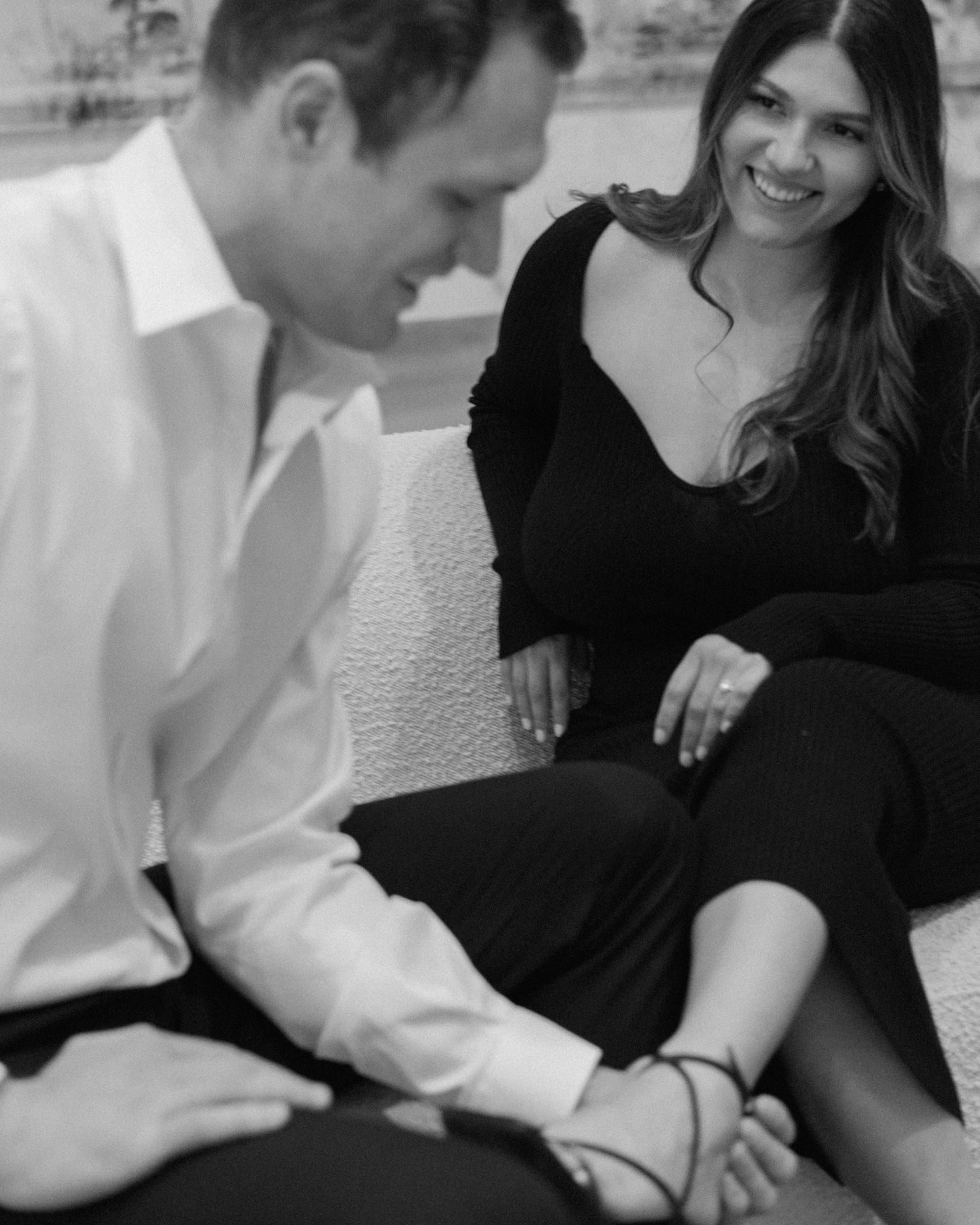 Elegant engaged couple smiling and embracing in downtown Louisville, with the woman showing her engagement ring