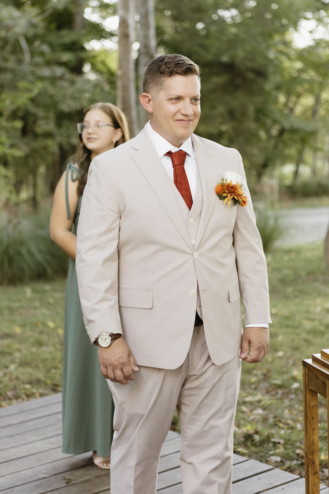 Wedding party members walk along a wooden boardwalk surrounded by greenery.