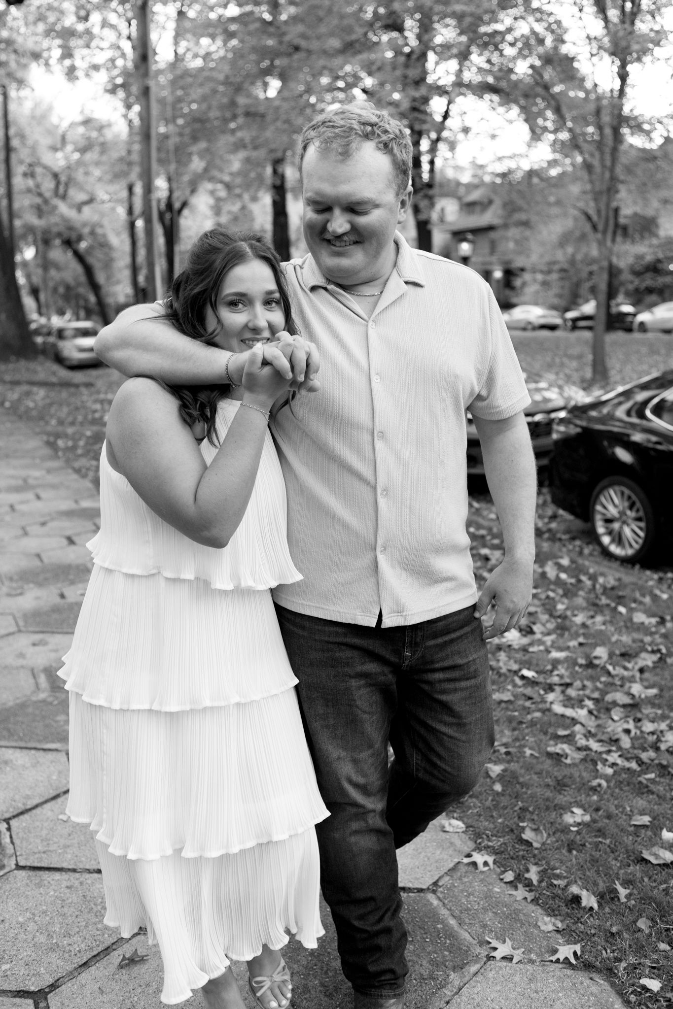 A romantic couple shares joyful moments together on an autumn day in black and white photography.