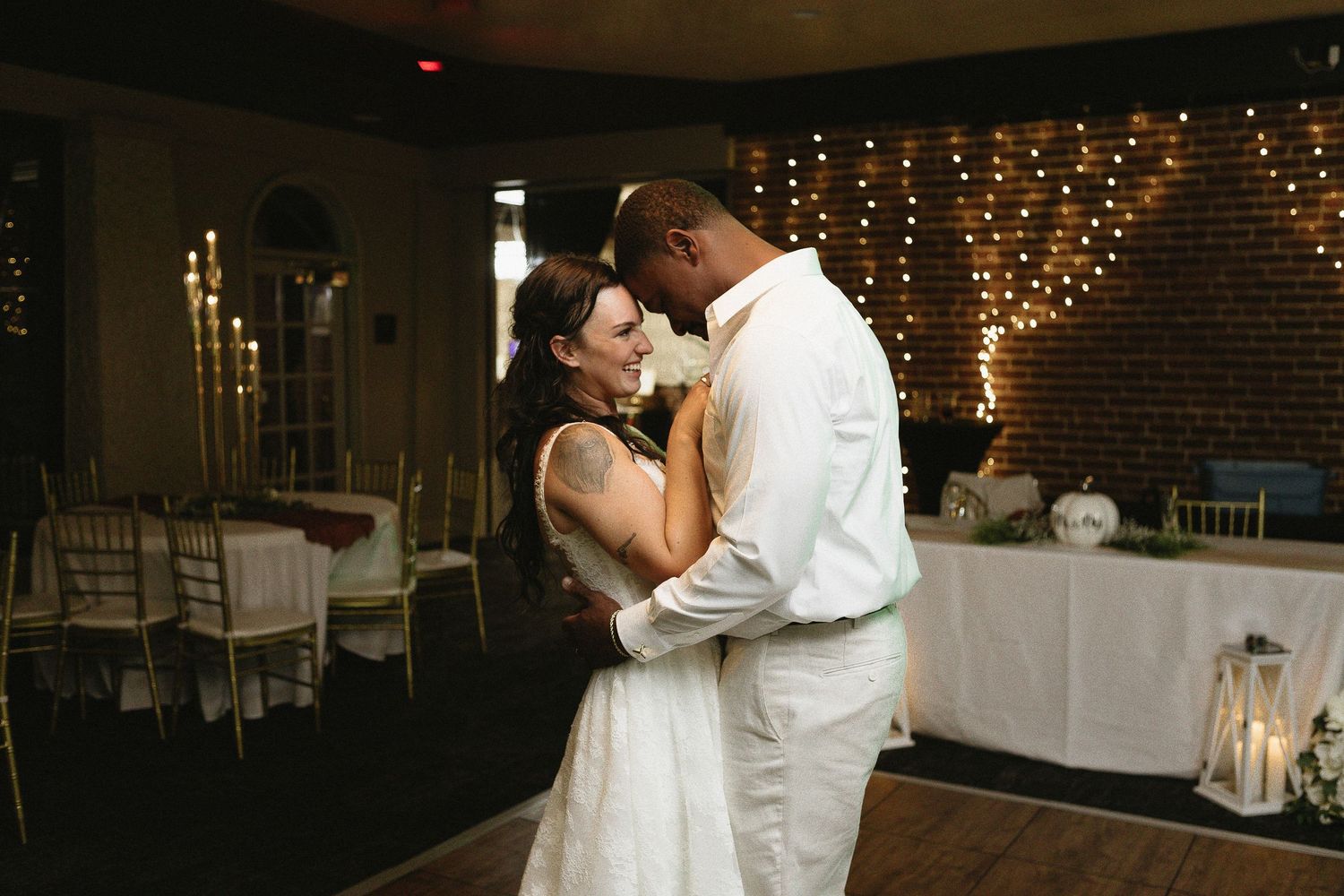 Romantic first dance sequence in a beautifully lit reception venue with string lights.