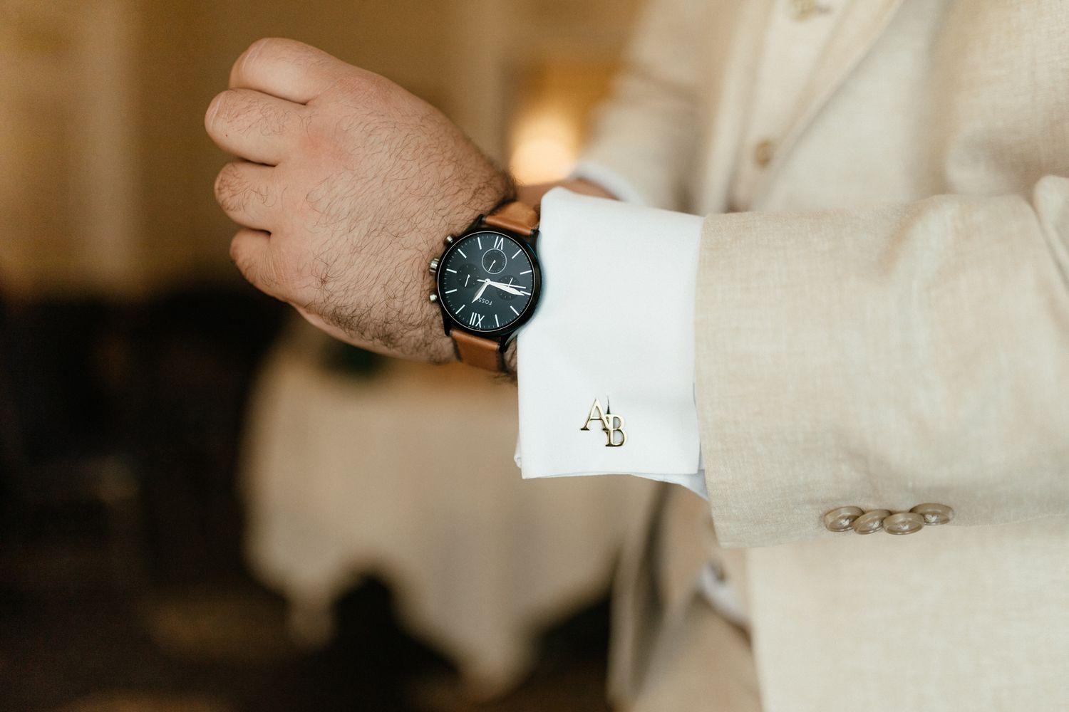 A close-up shot of a white dress shirt cuff with cufflinks and a black analog watch.