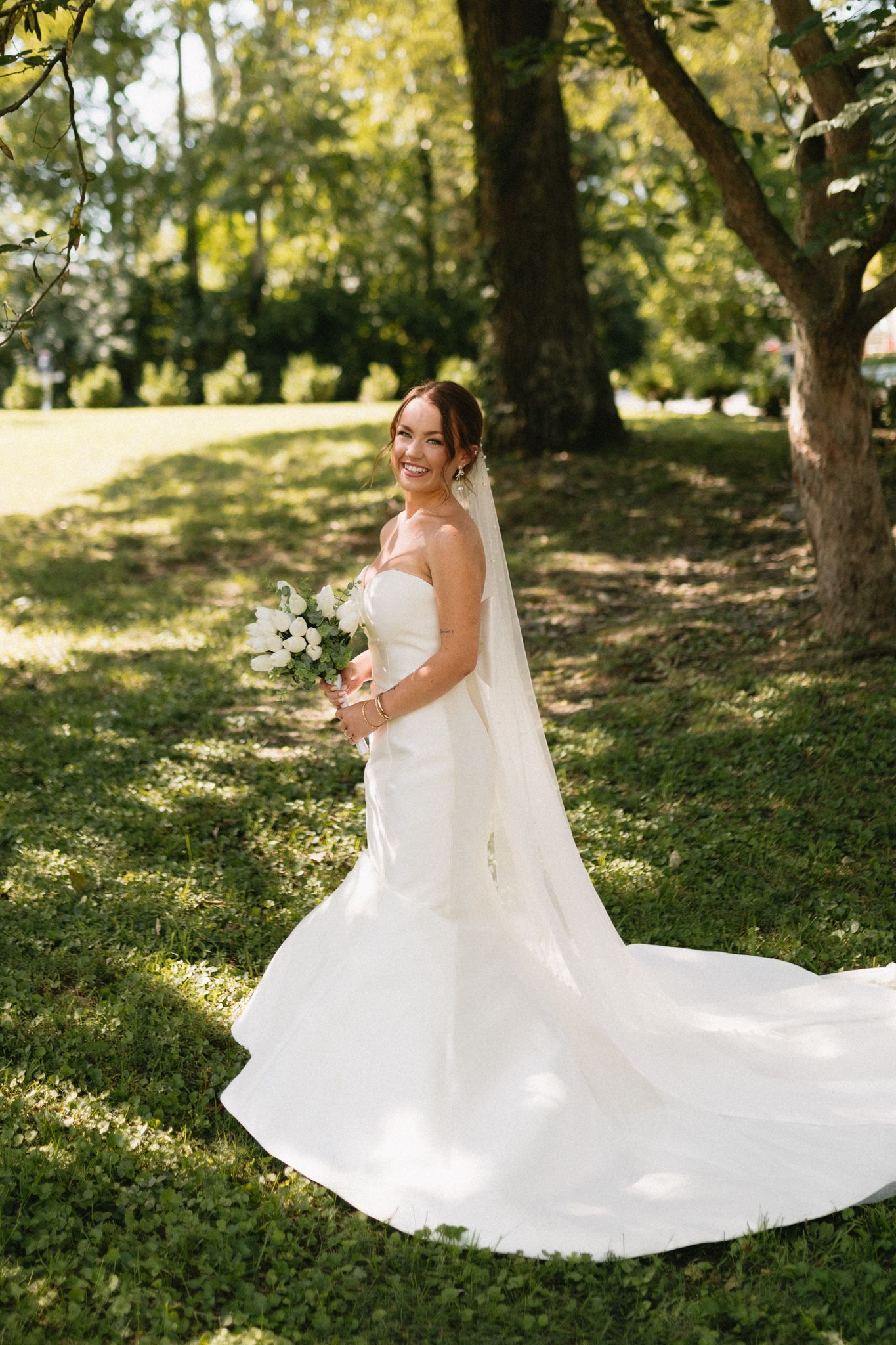 beautiful bride standing on lush green grass around blooming flowers