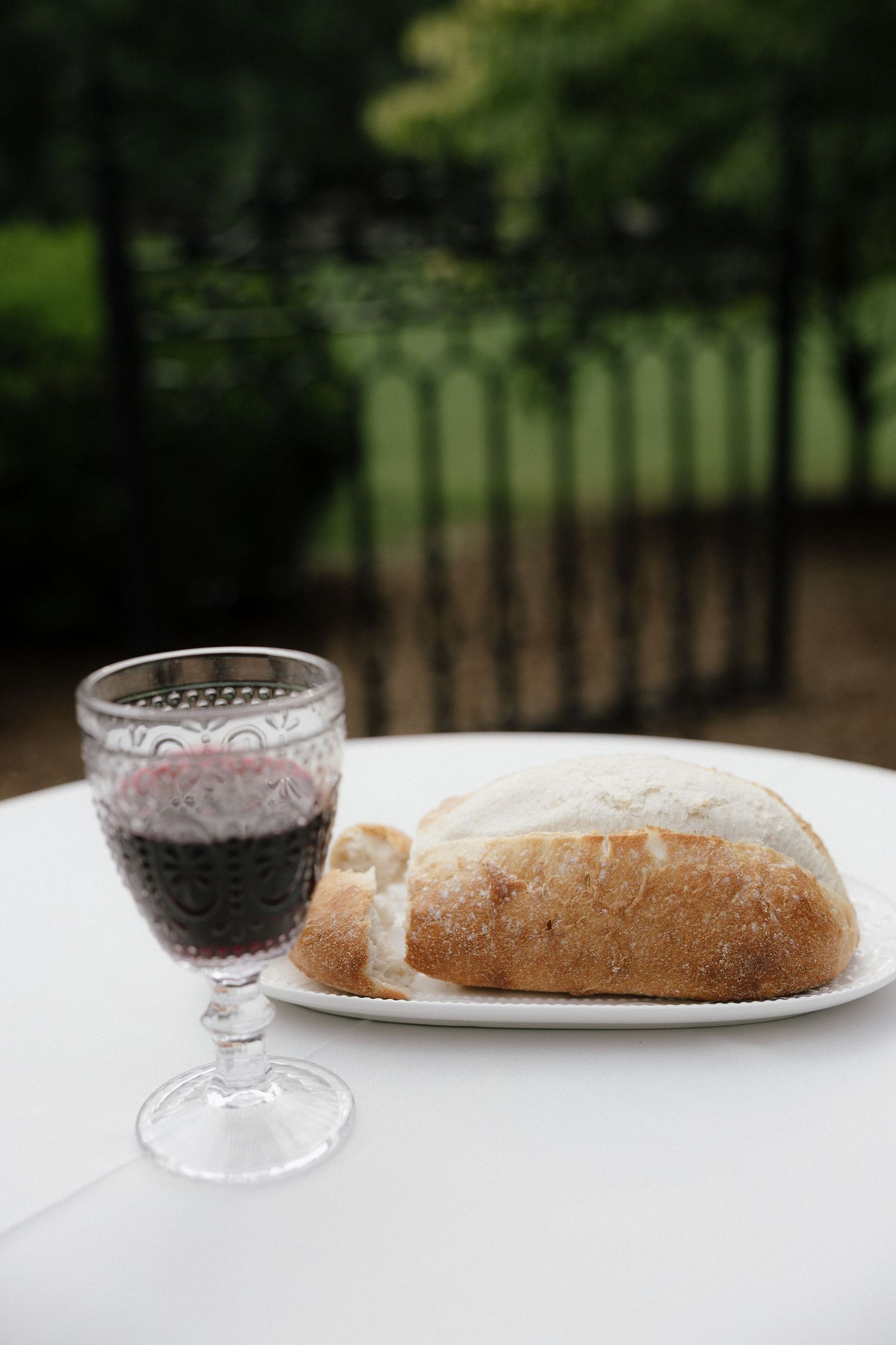 Elegant wedding communion with crystal glass of red wine and artisan bread loaf on white tablecloth.
