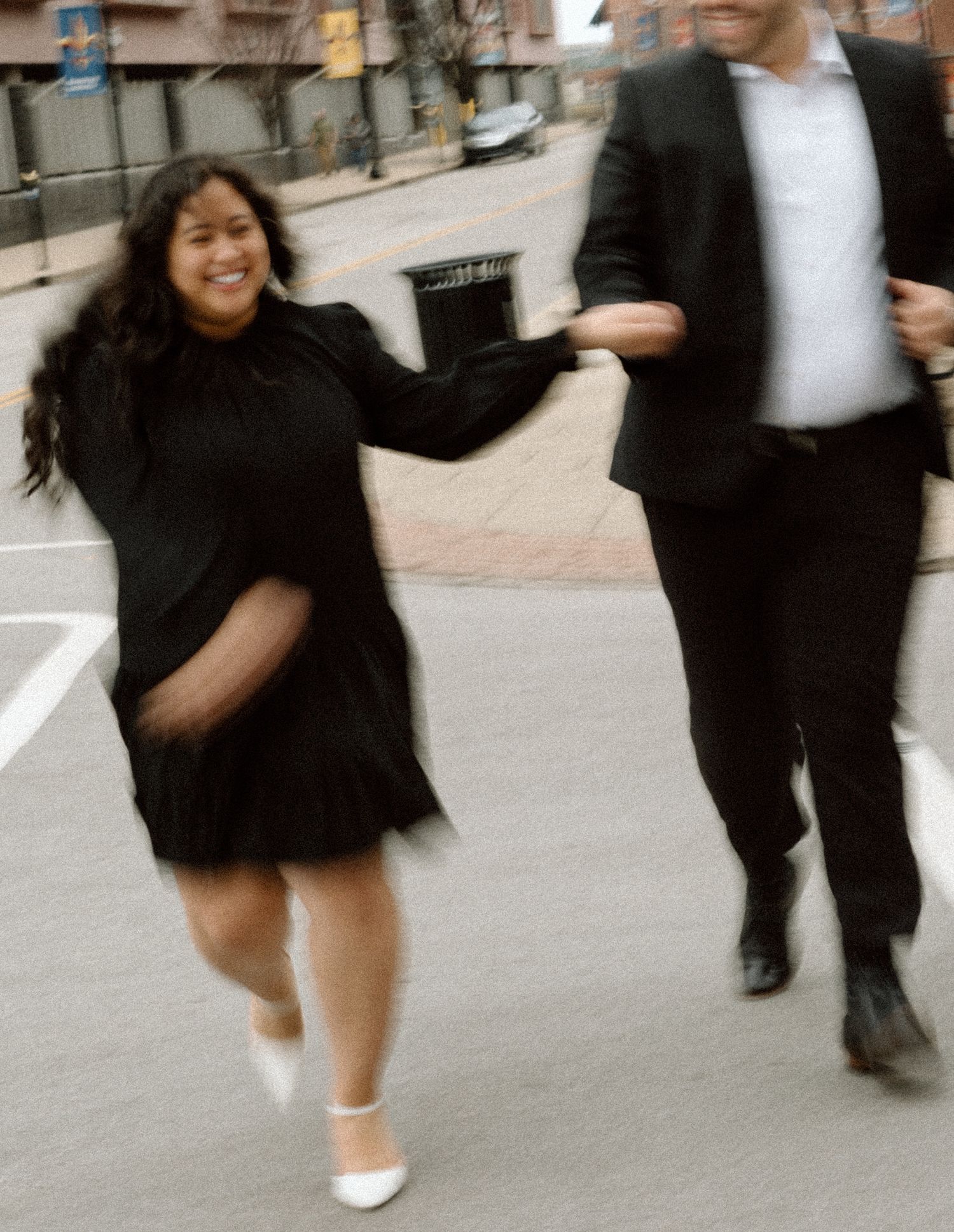 Elegant engaged couple smiling and embracing in downtown Louisville, with the woman showing her engagement ring