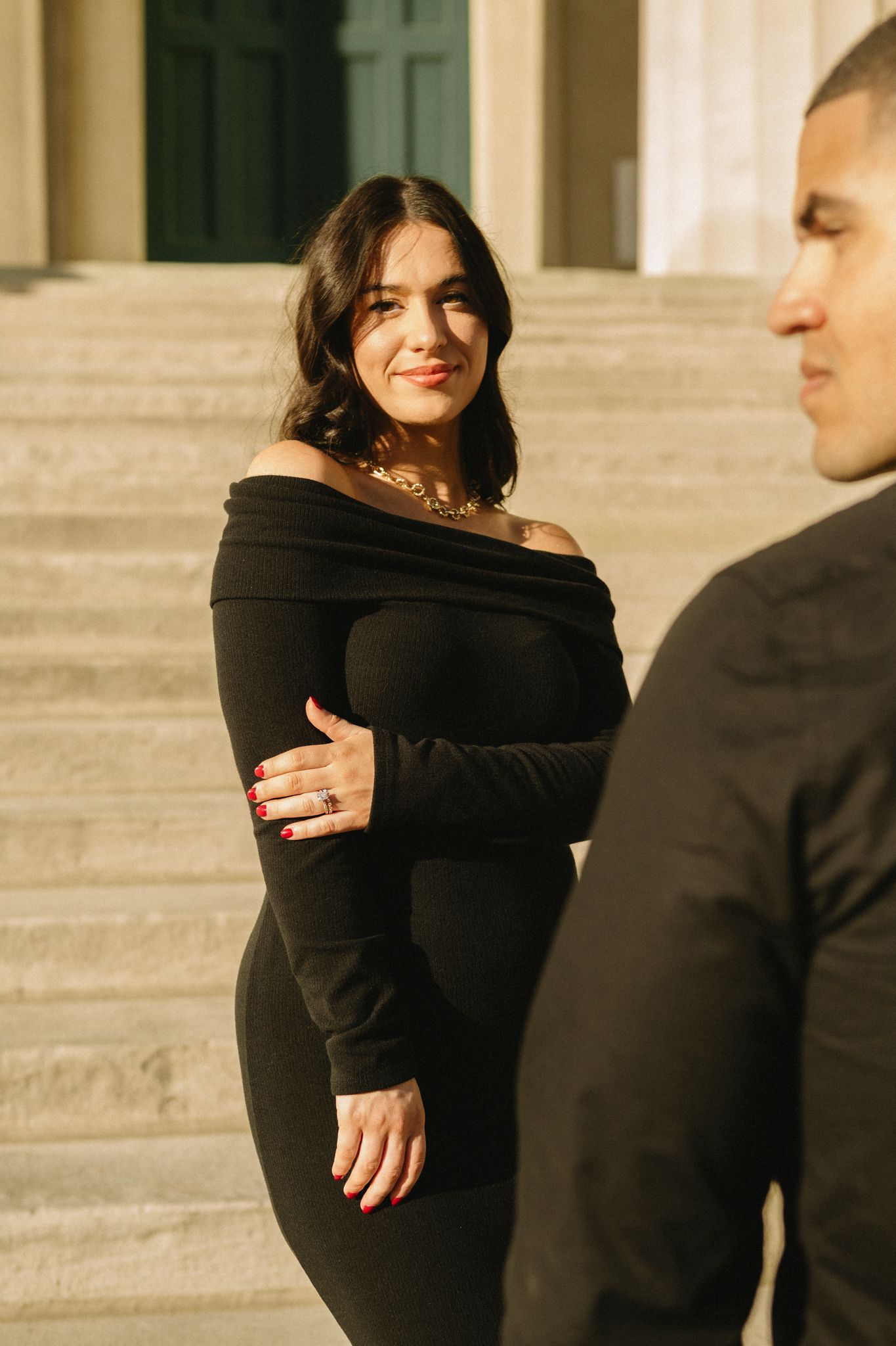 A couple in matching black outfits poses on stone steps during a golden hour photo session.