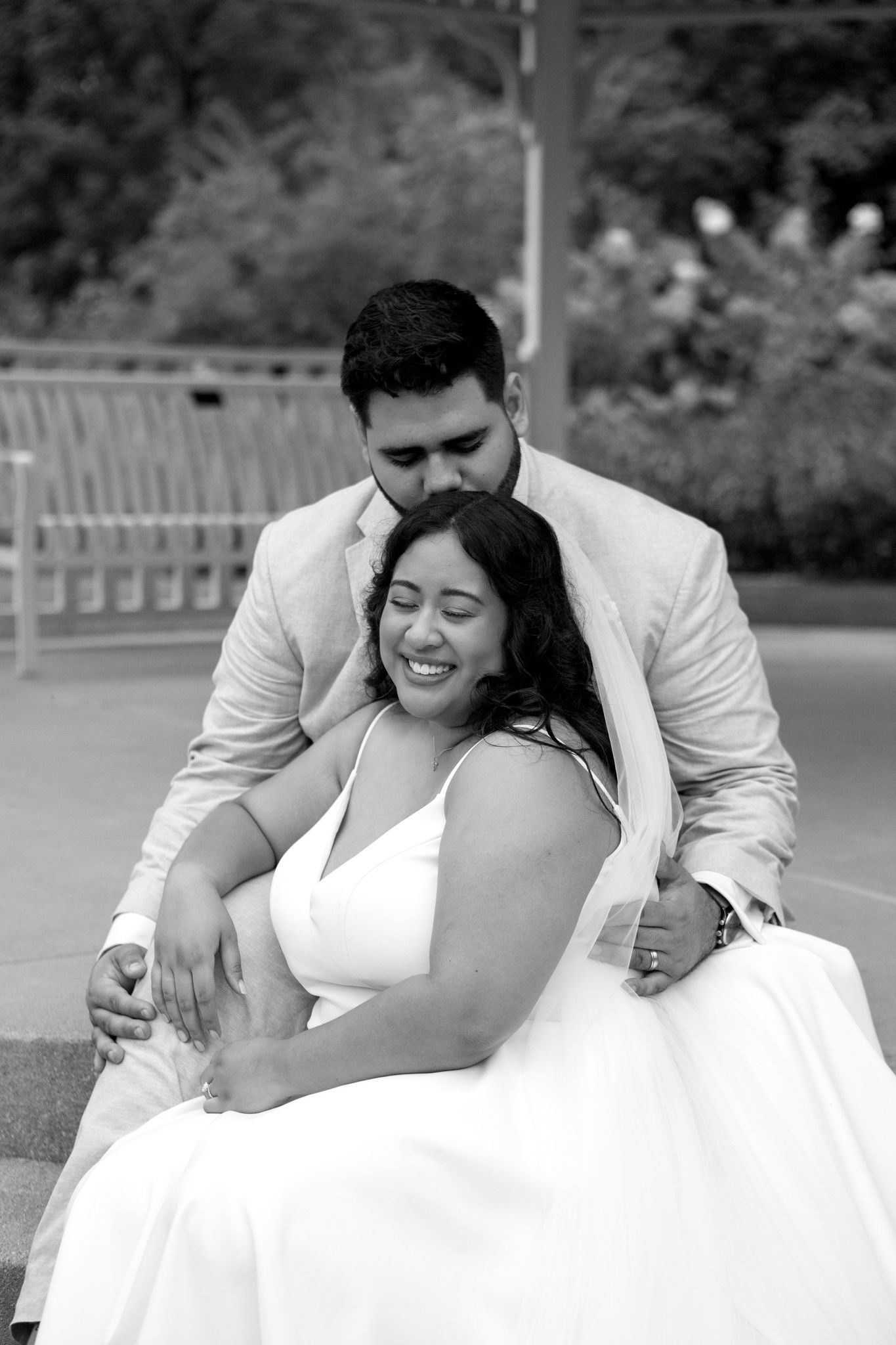 A loving couple shares an intimate black and white moment together outdoors during their wedding celebration.