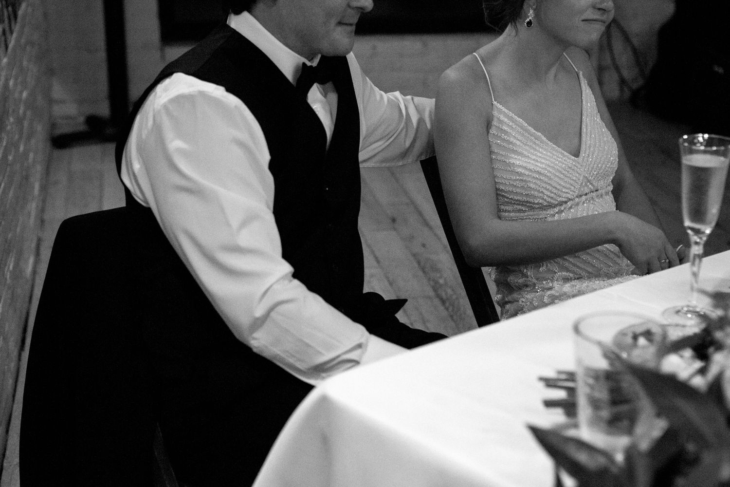 Black and white candid shot of a couple at their wedding reception table.