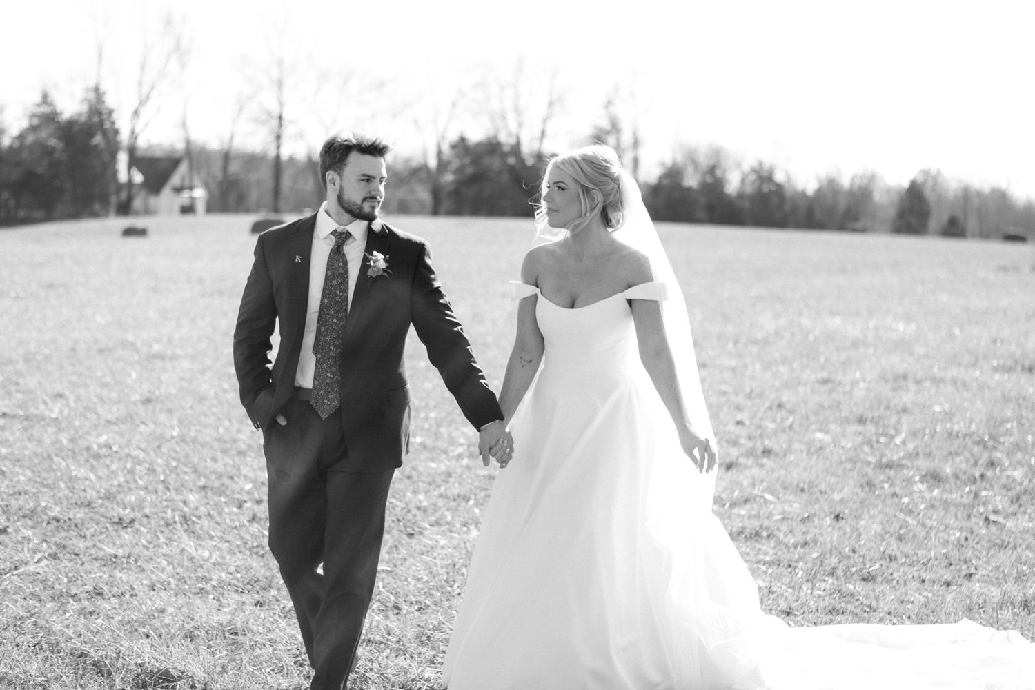 Bride and groom walking through a sunny field at Silo Farms, captured in black and white. Photo by Joia Lyn, KY wedding