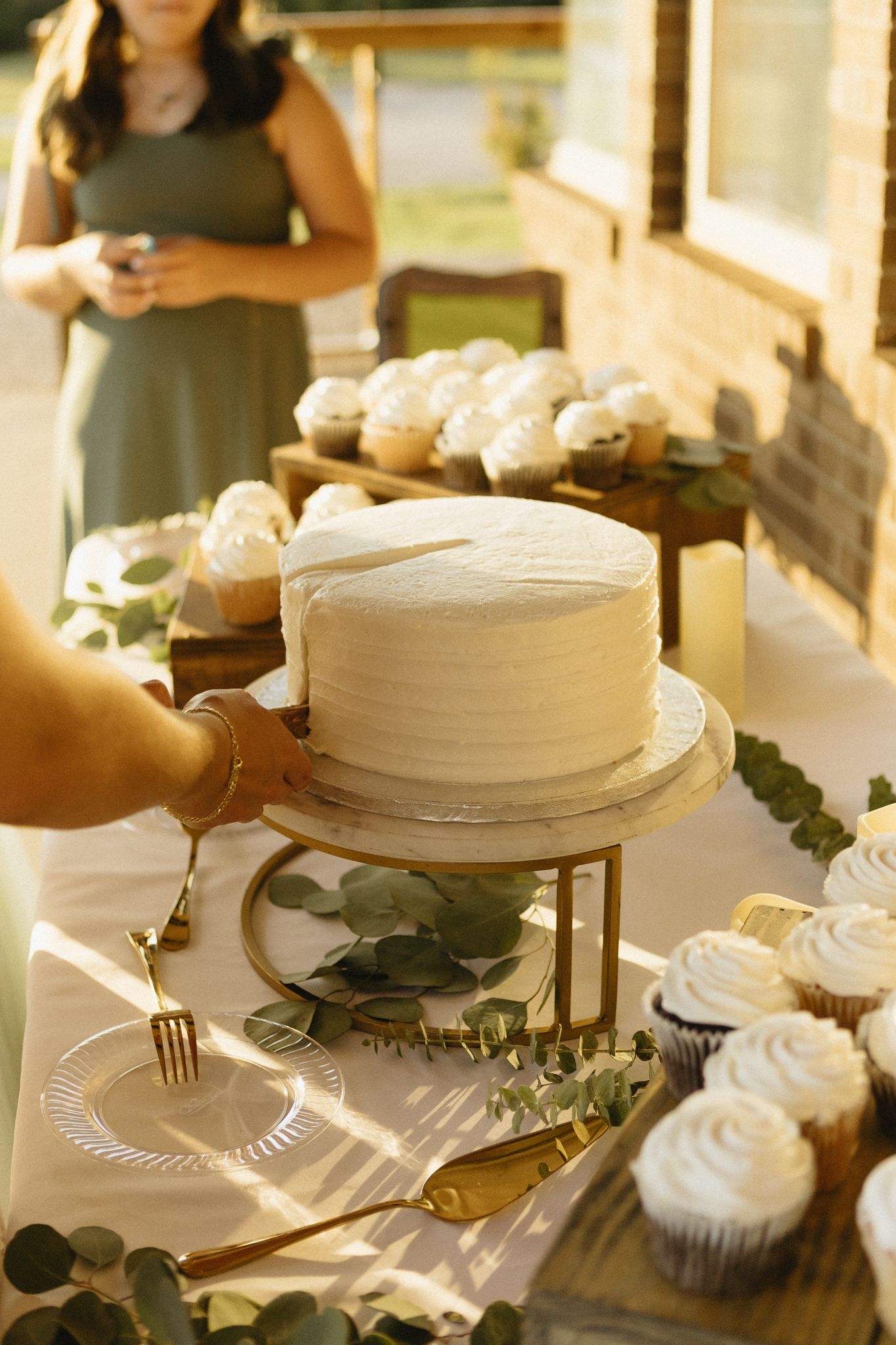 White wedding cakes and desserts displayed on an elegant table with greenery accents.
