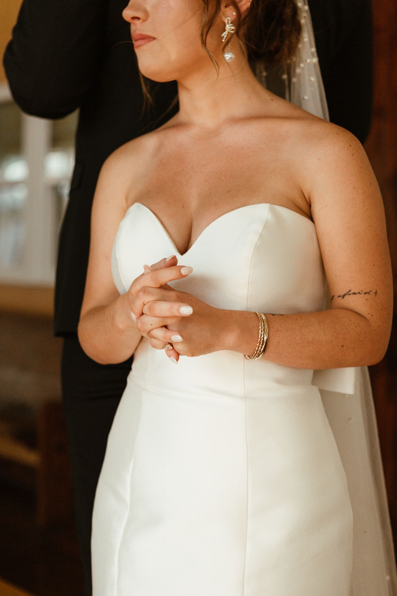 bride in bridal gown standing next to groom showing wedding ring