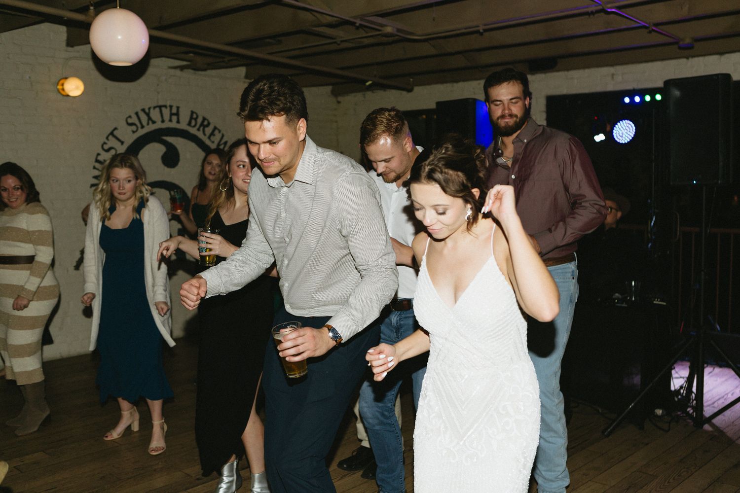 Wedding guests dancing and celebrating together on the dance floor during a reception celebration.