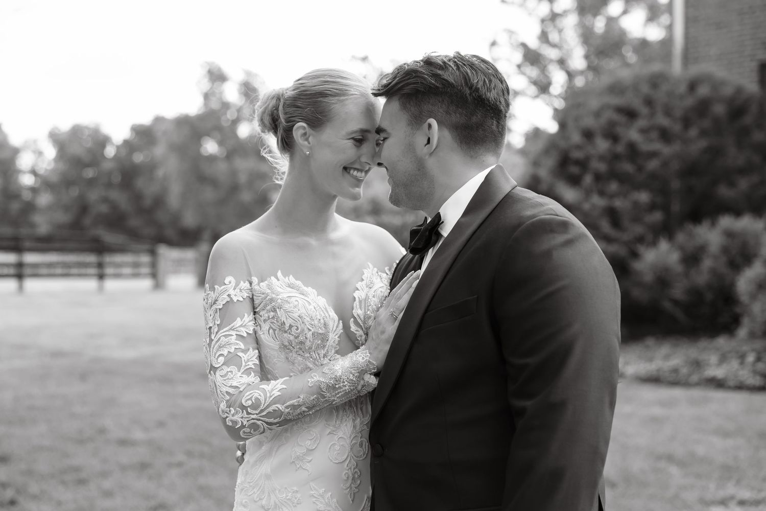 A bride and groom share an intimate moment outdoors in black and white wedding portrait photography.