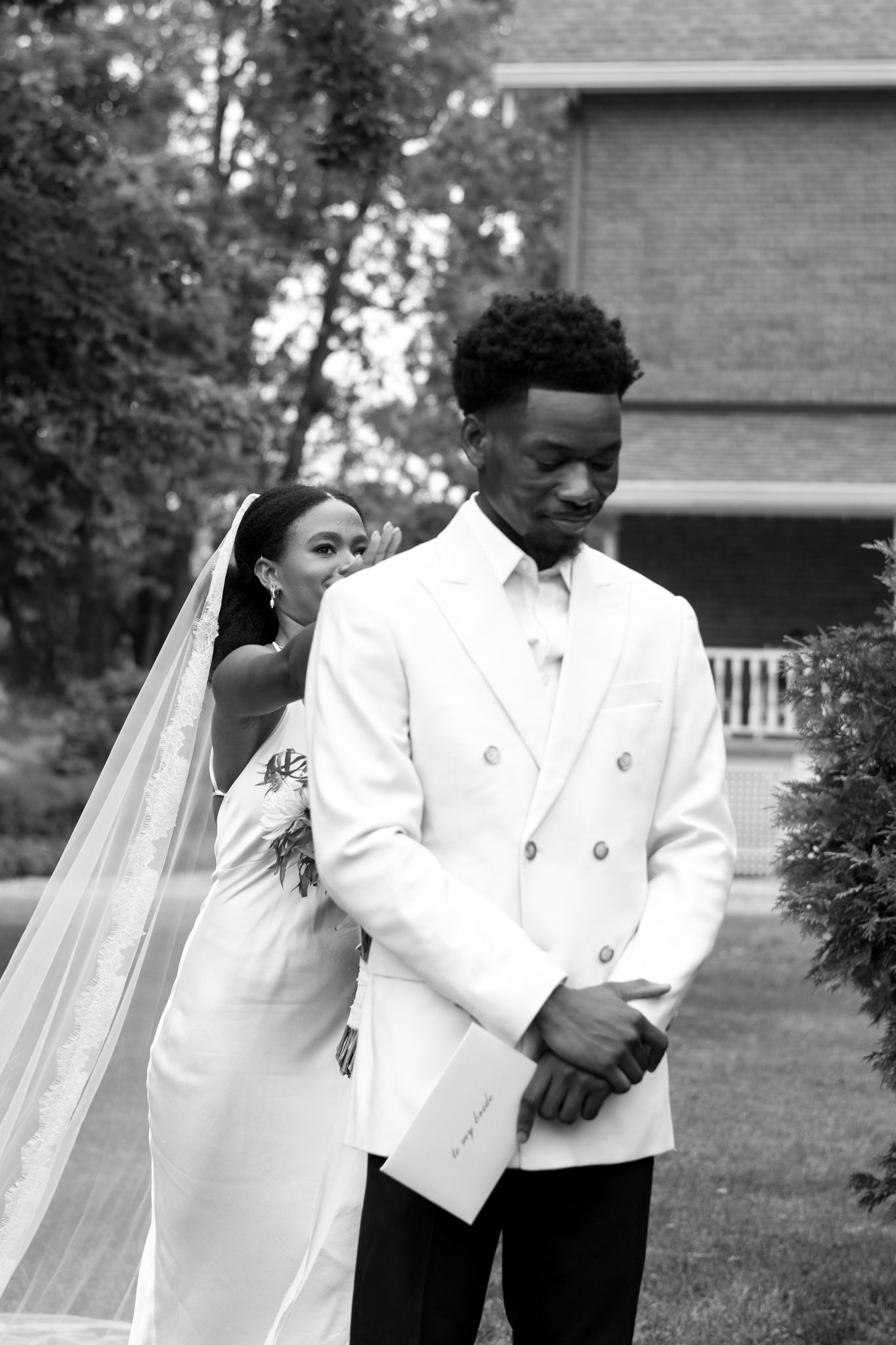Classic black and white first look wedding moment captured outdoors.