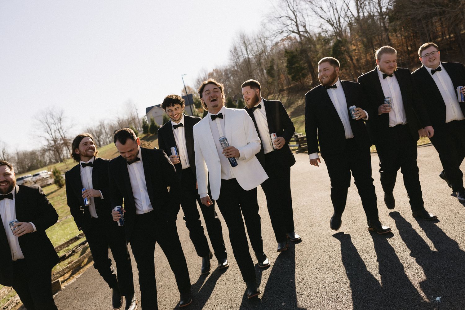 Groomsmen in black suits lined up against a winter landscape backdrop.