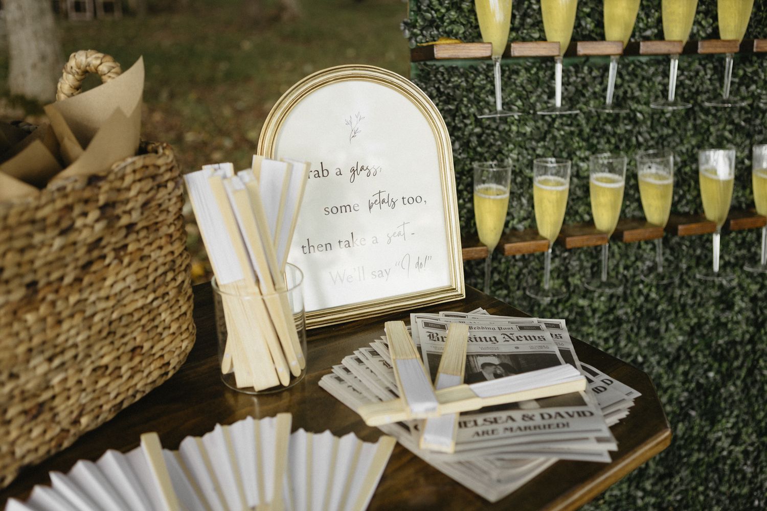 Wedding reception details with champagne bottles and guest cards arranged on a rustic outdoor display.