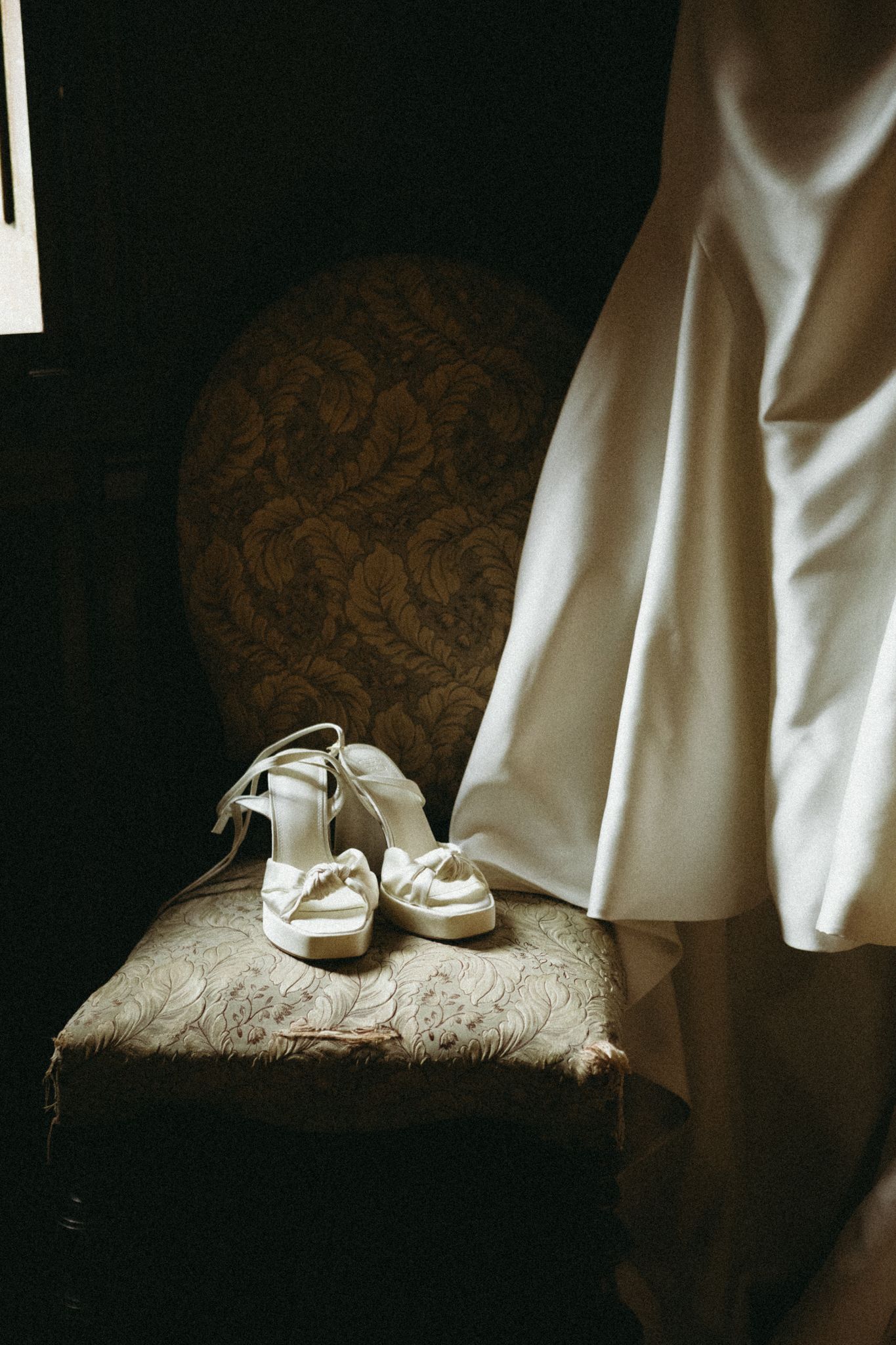 White bridal shoes rest elegantly on an ornate damask chair against a dark background in a series of artistic shots.