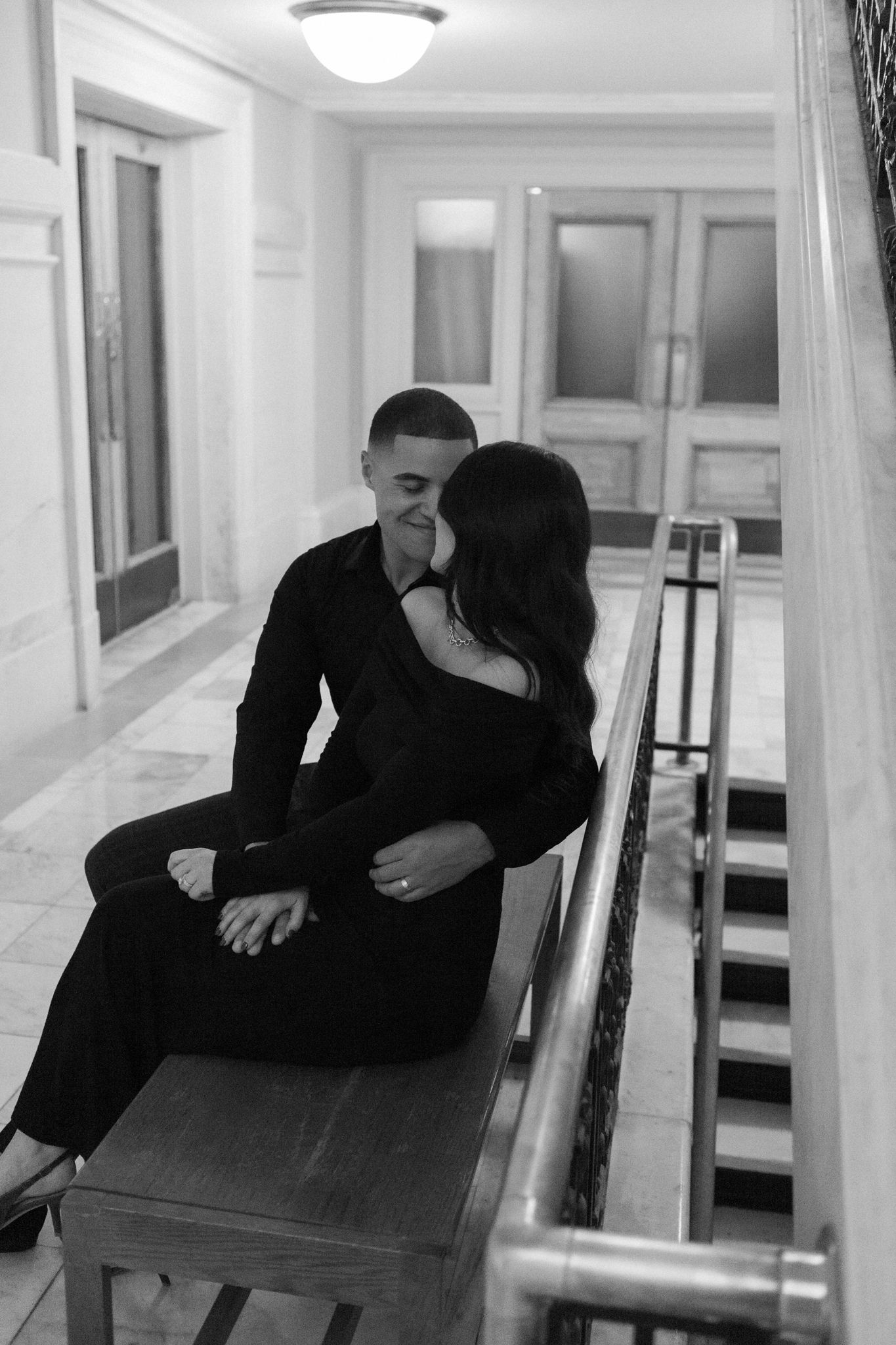 A romantic black and white photo of a couple sharing an intimate moment in a hallway.