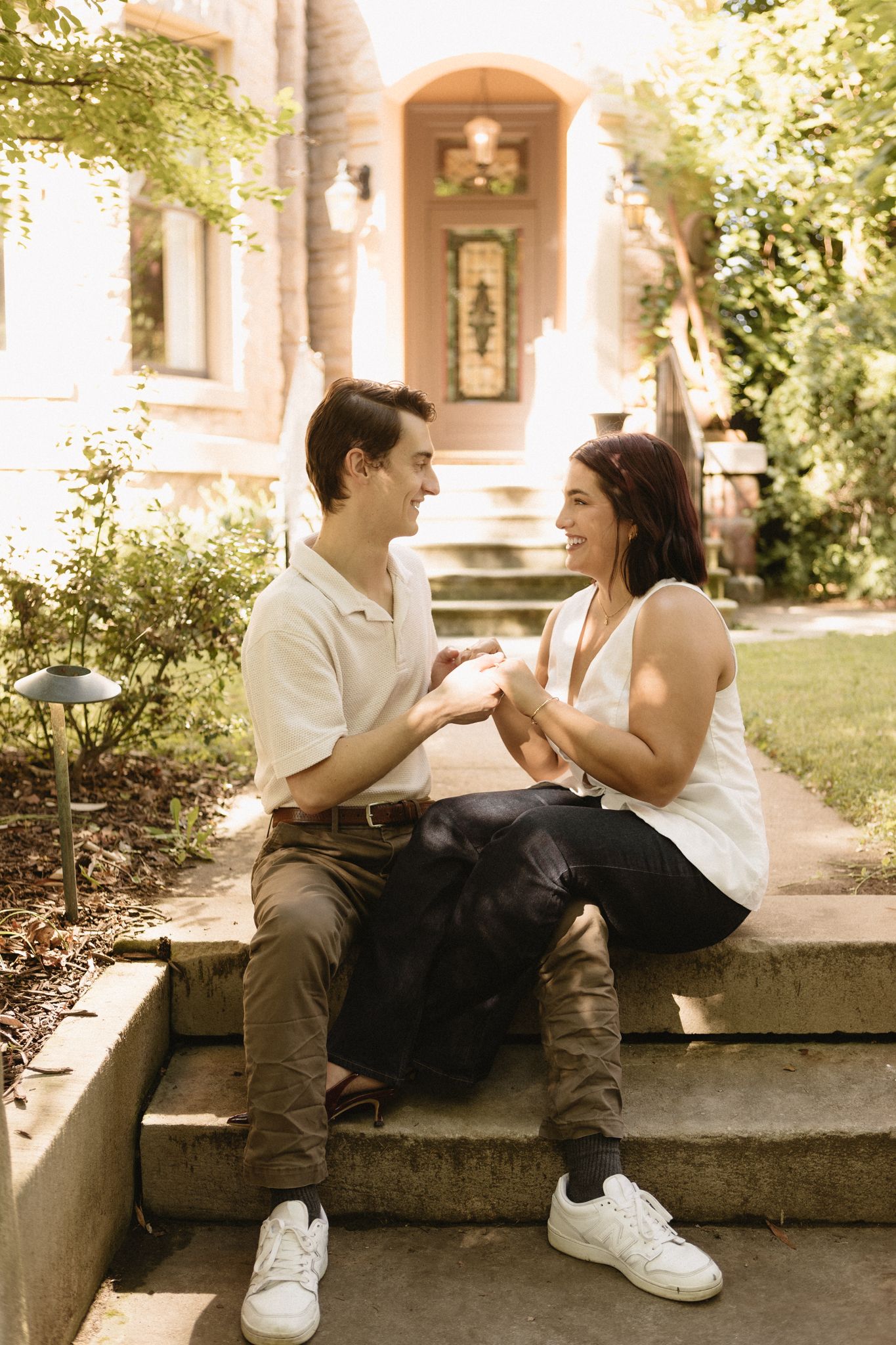 A couple sits together on stone steps in a romantic outdoor setting with a sepia-toned filter effect.