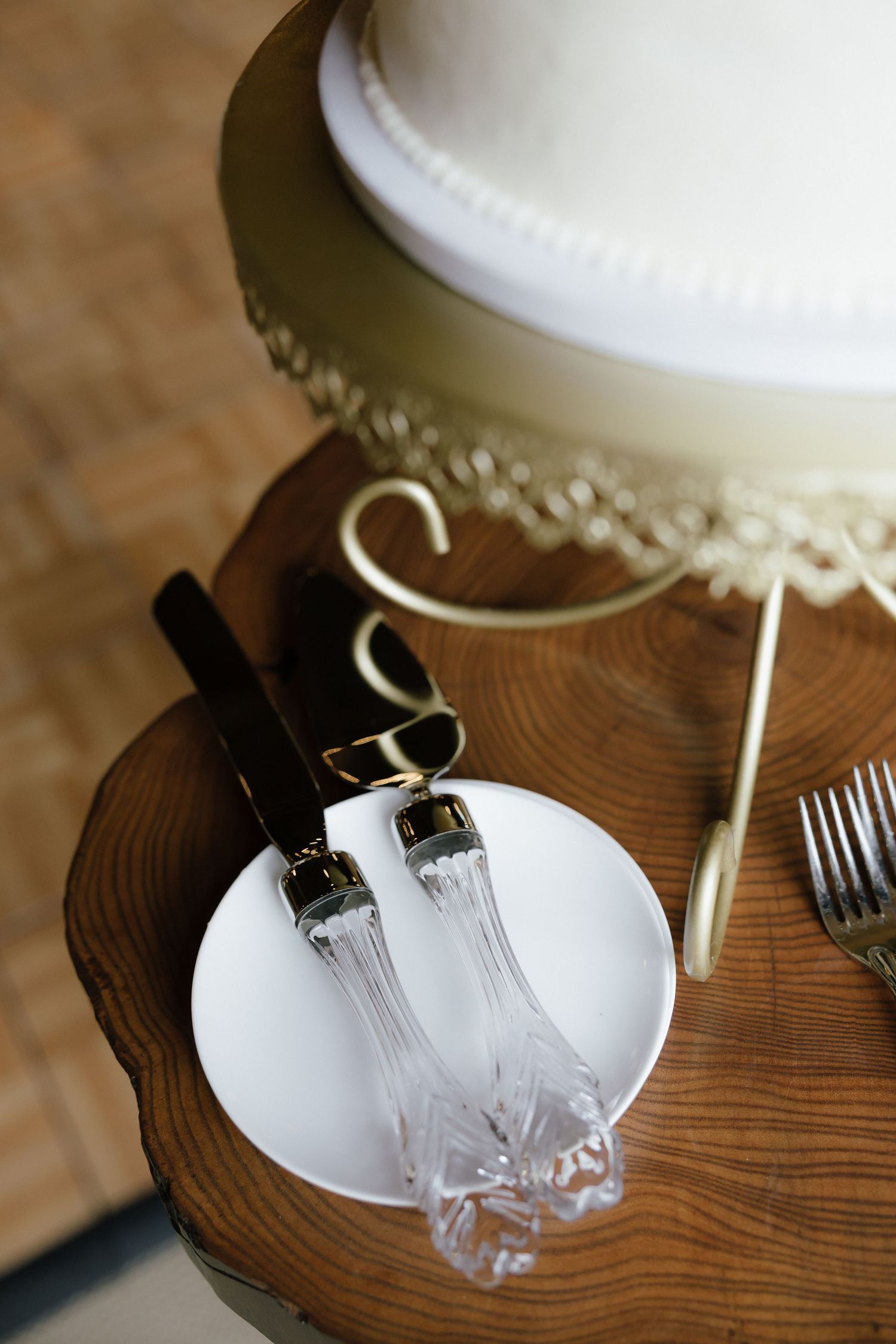 Elegant wedding cake with crystal cake cutting set on rustic wood table with gold accents.