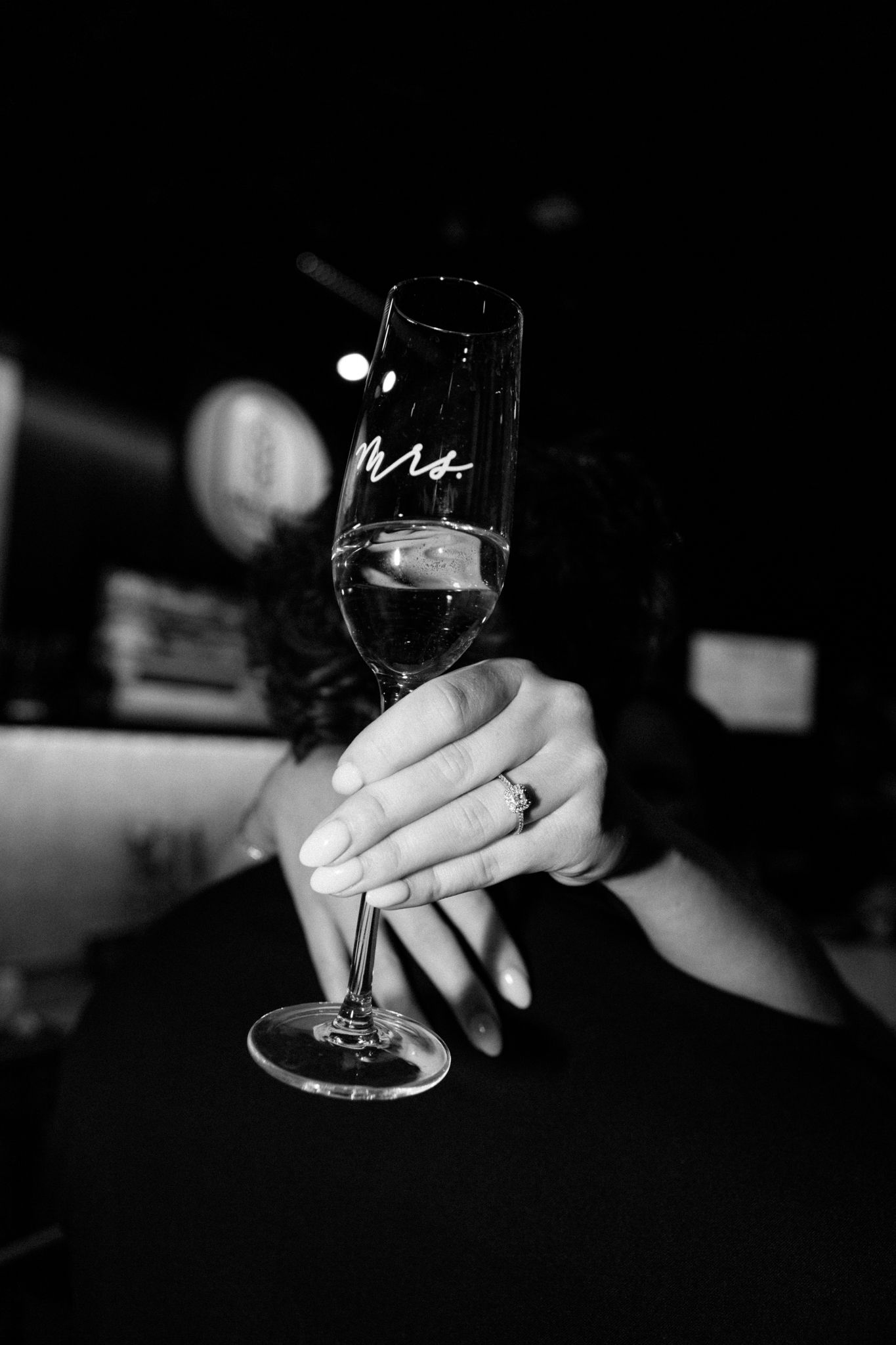 Engaged couple, with the woman showing her engagement ring and wine glass, captured in downtown Louisville
