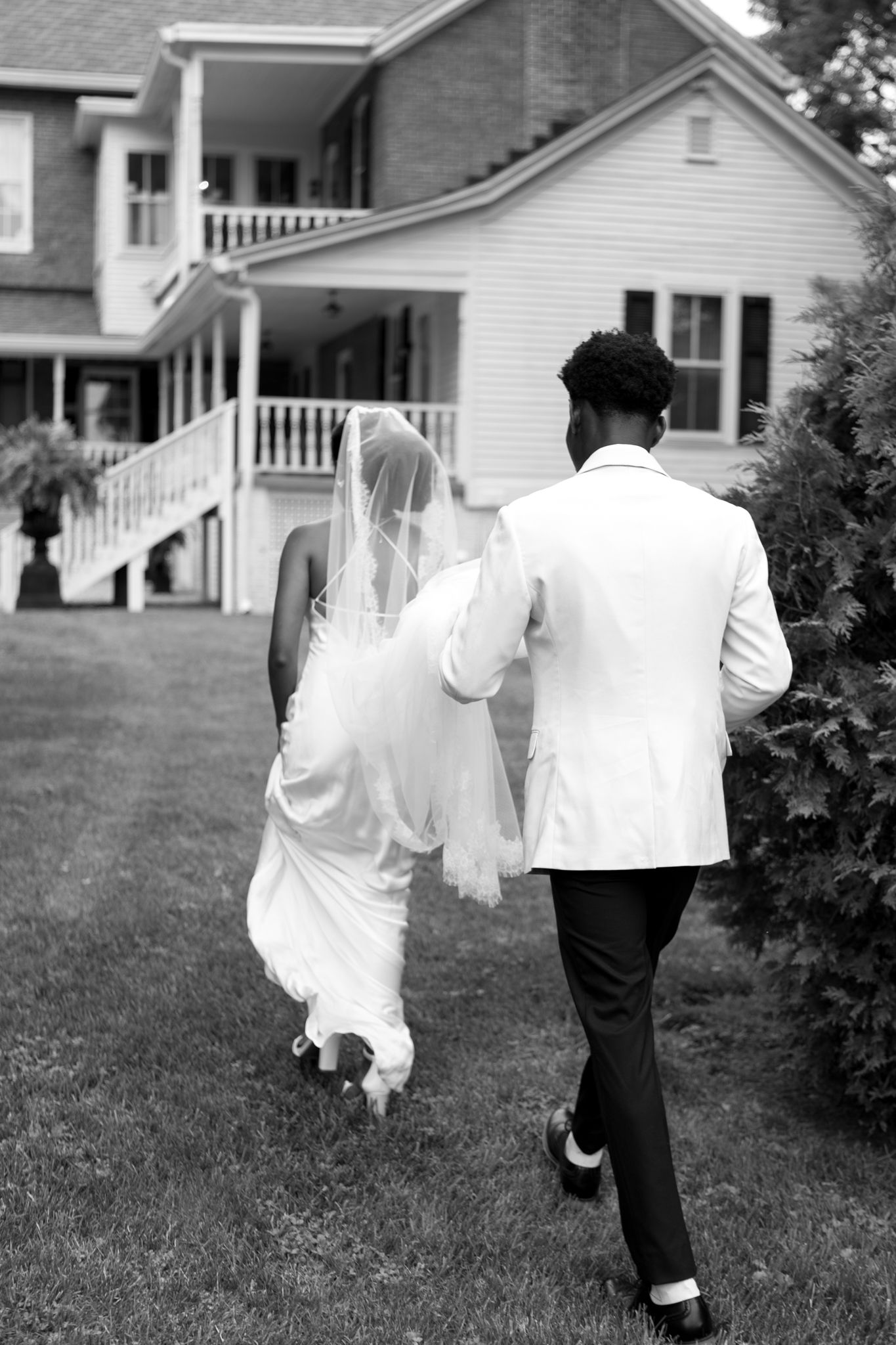 Black and white photos showing couple walking across lawn of white farmhouse.