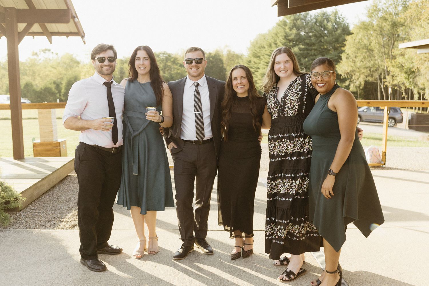 Wedding guests in formal attire gathered outside for group photos.