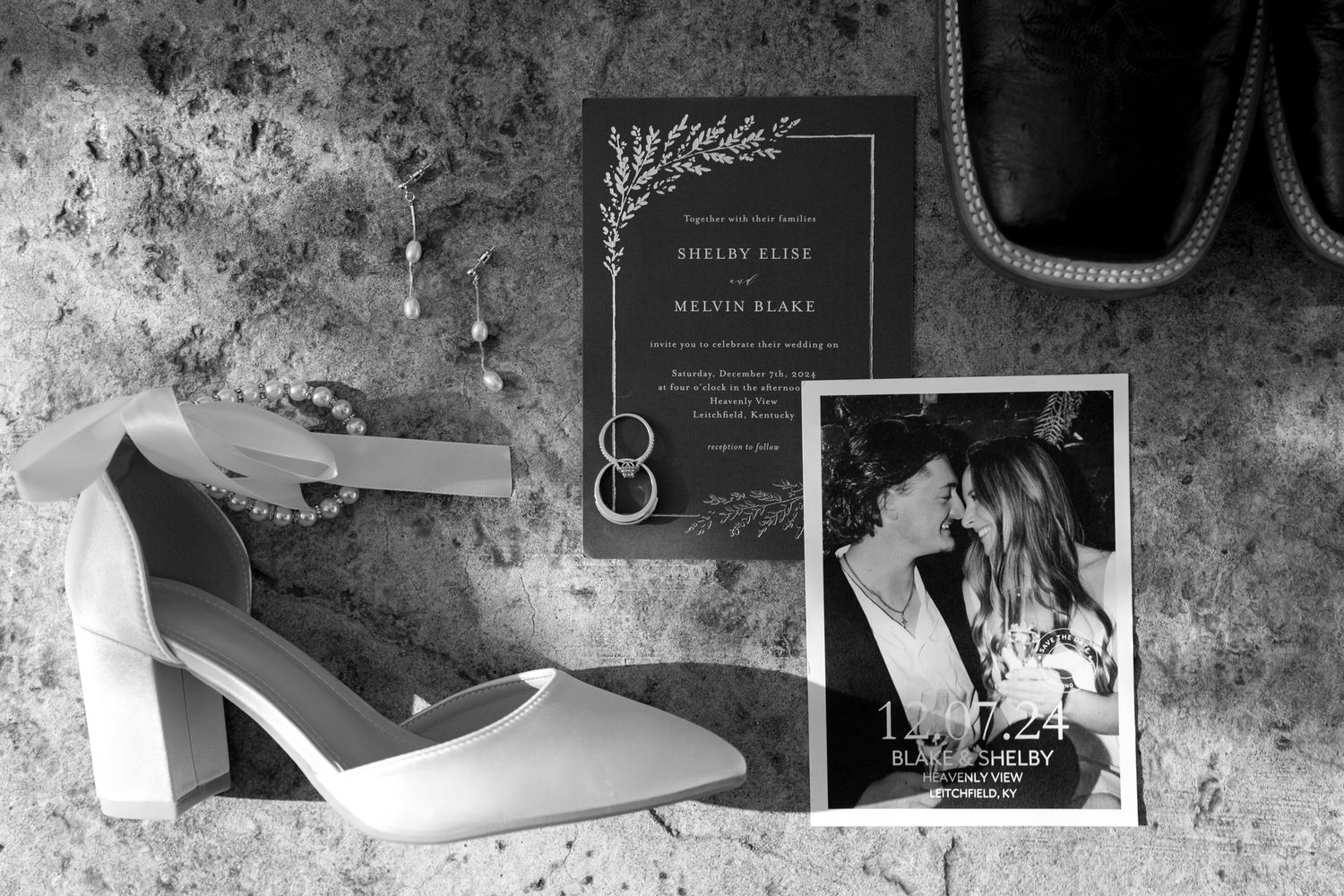 Wedding detail flatlay with invitation suite and accessories in monochromatic style.