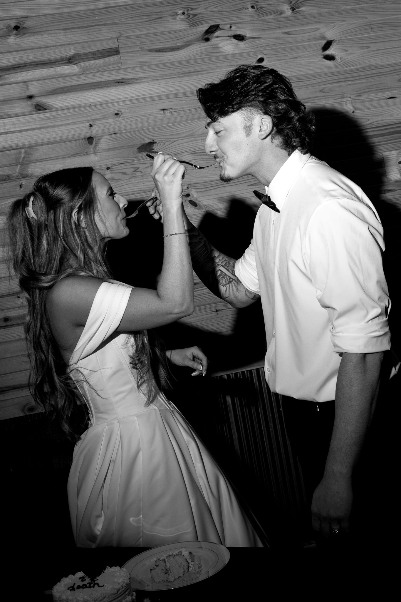 Black and white photos showing a couple playfully feeding each other cake at their wedding reception.