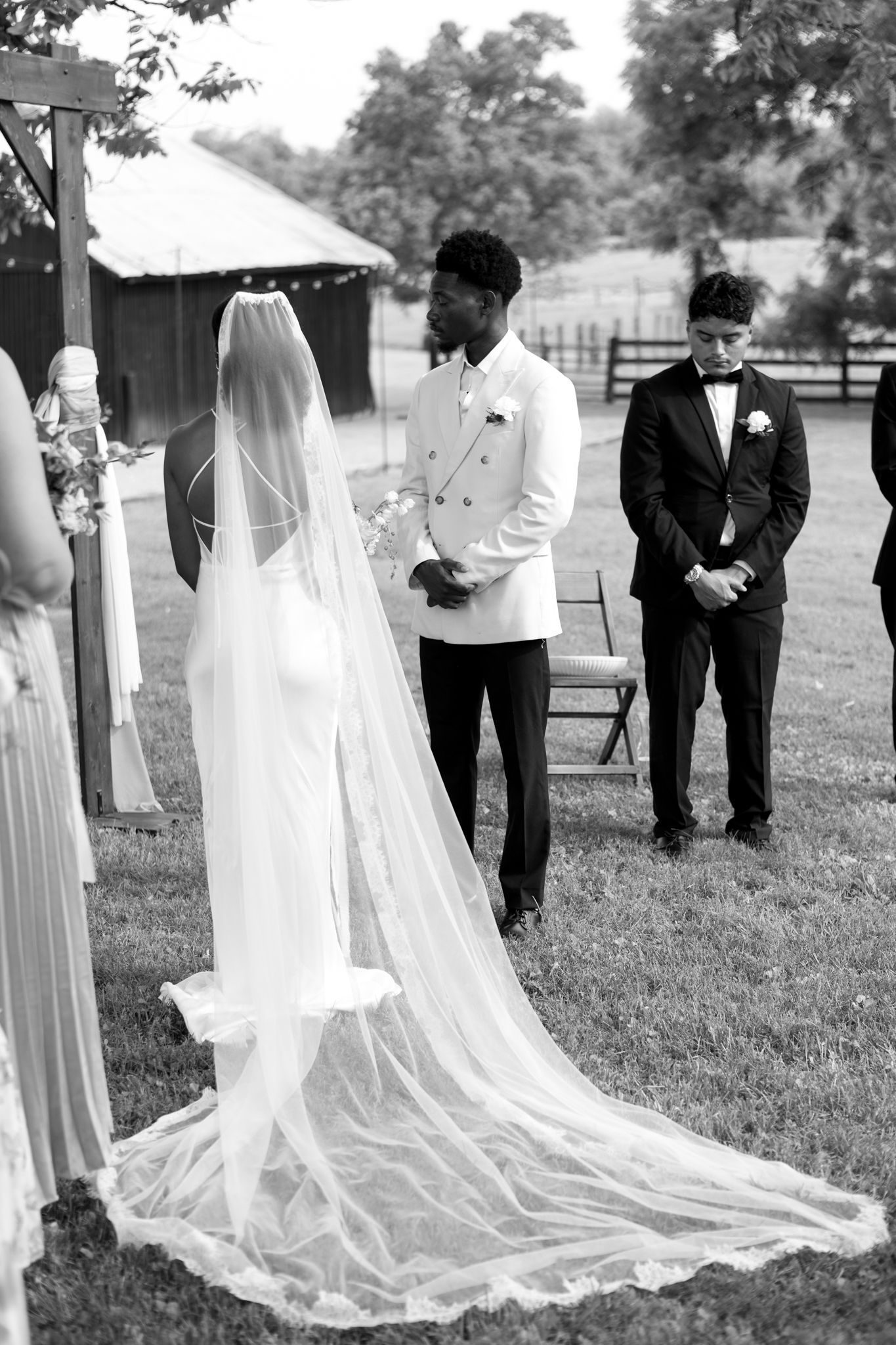Wedding ceremony lineup with flowing white veils and dresses in black and white photography.