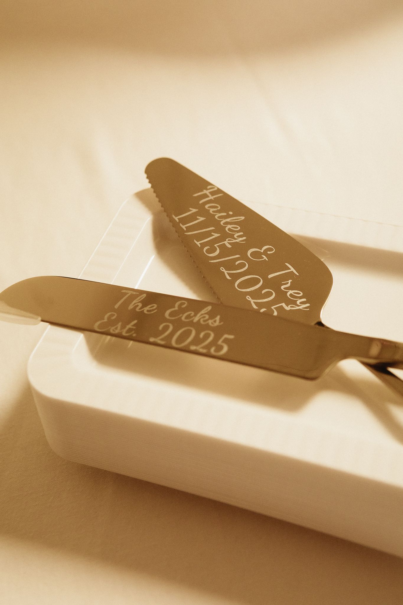 Engraved gold cake server with wedding date details in warm sepia tones.