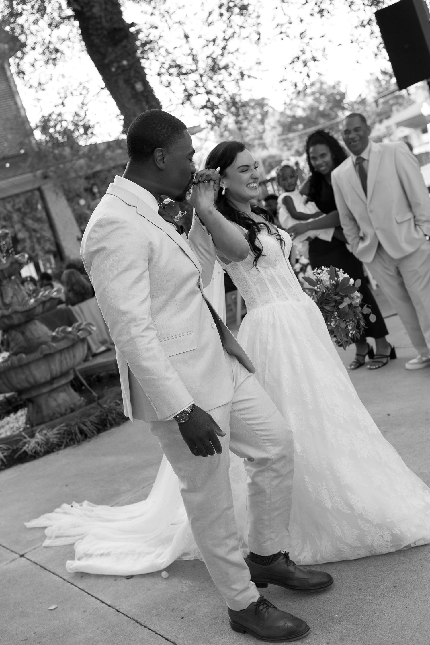 Black and white photo showing couples dancing on a patio during a wedding reception.