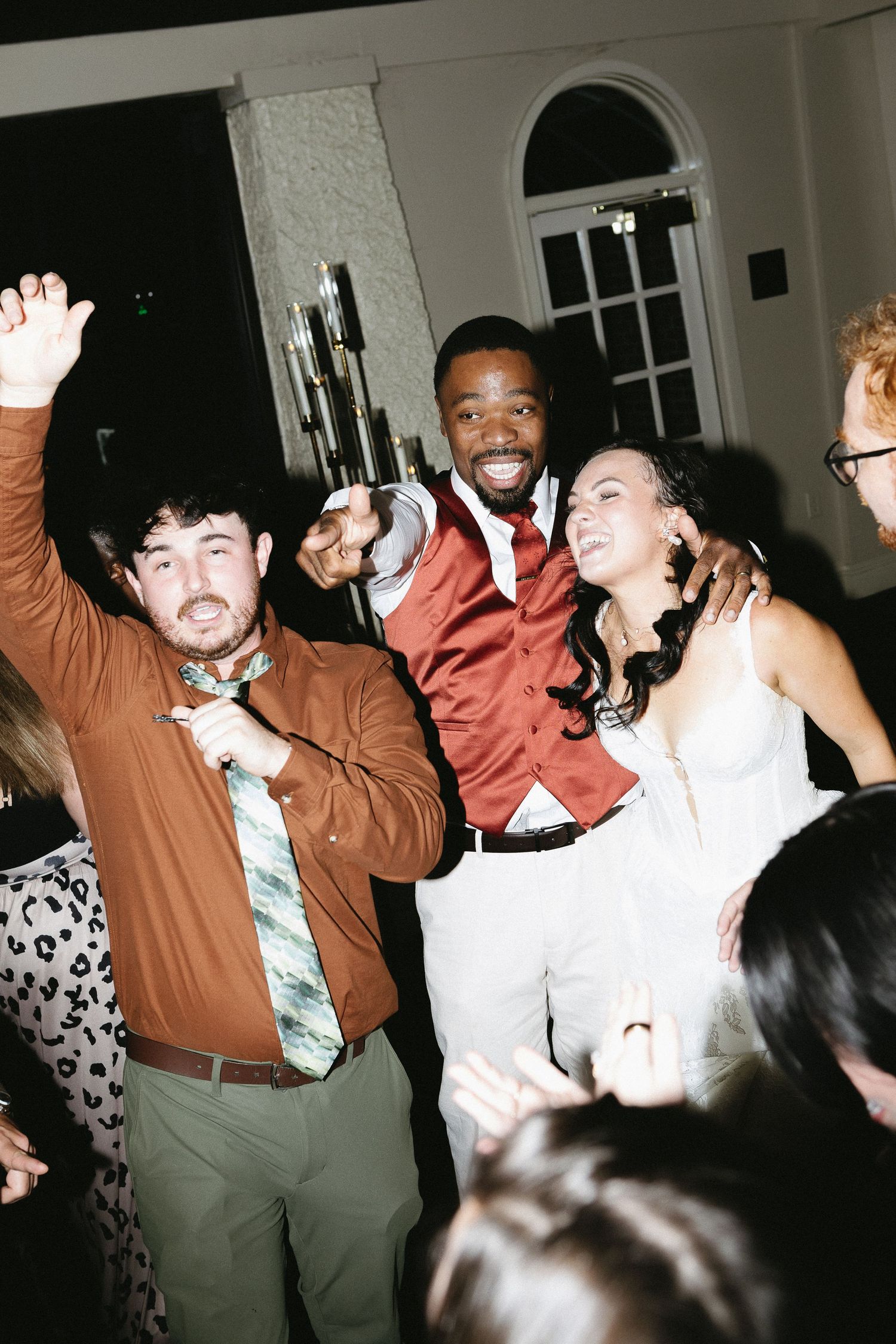 Wedding guests dancing and celebrating at a lively reception party.
