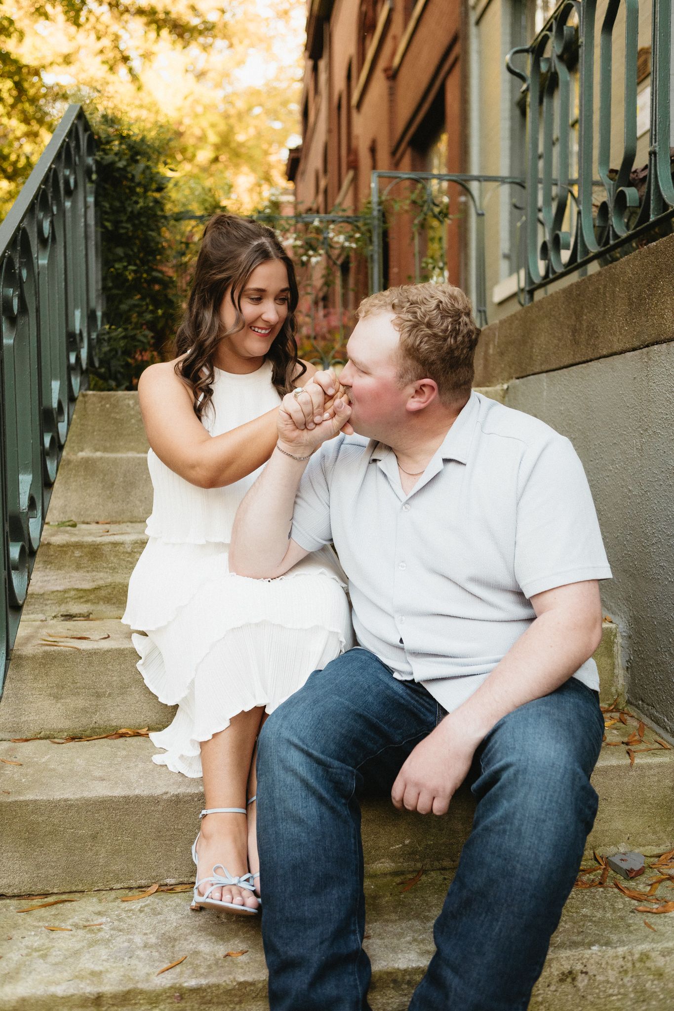 A playful moment shared on stone steps with ornate iron railings during a fall afternoon.