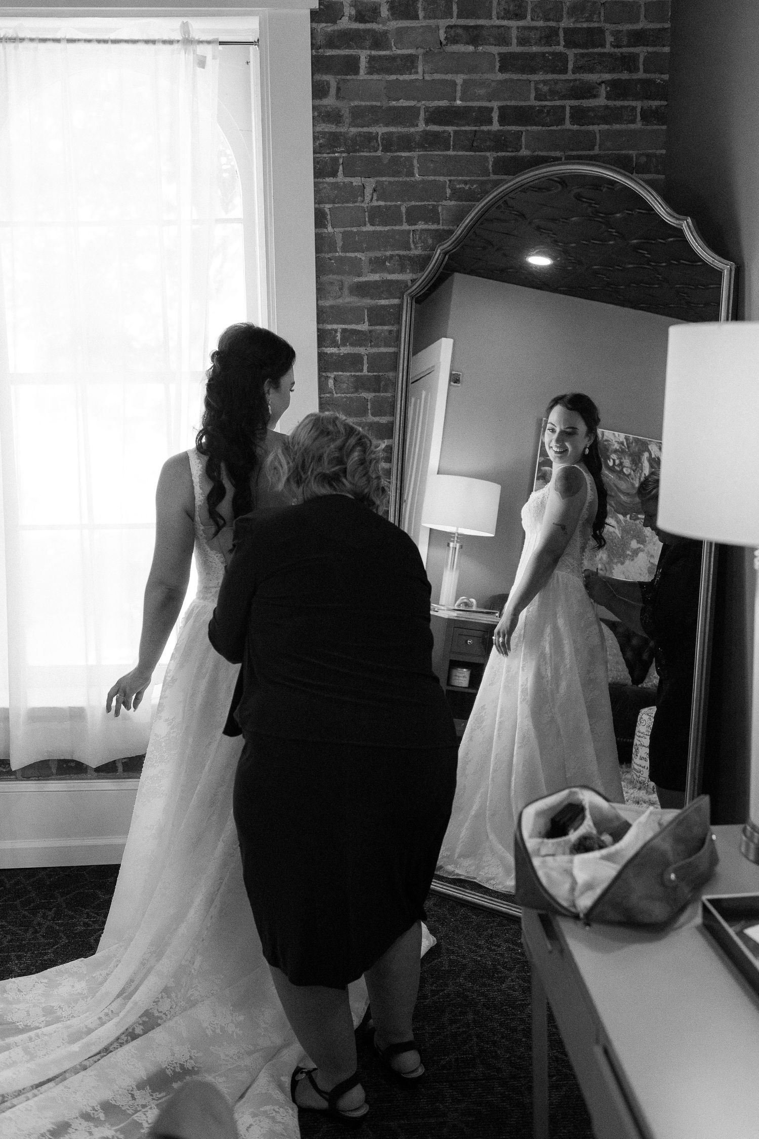 Wedding dress fitting session in a bridal boutique with exposed brick walls and mirrors.