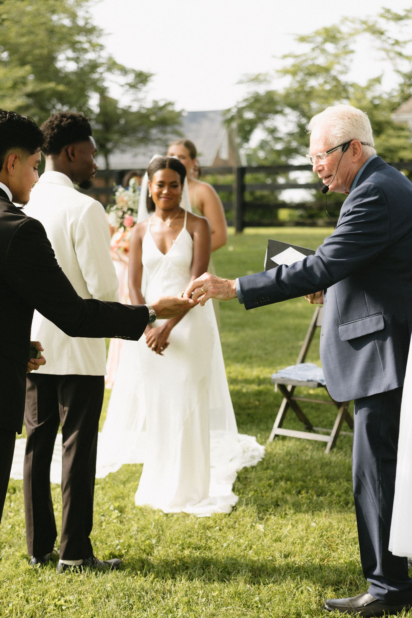An outdoor wedding ceremony on a grassy lawn with an officiant performing the service.