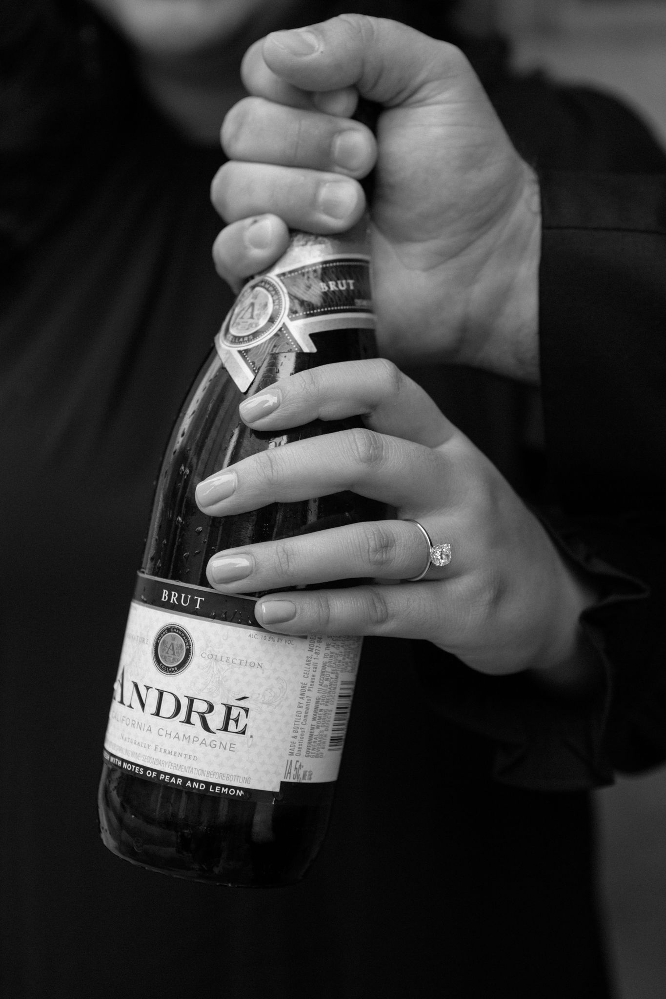Engaged couple celebrating with a bottle of Chandon, sharing a joyful moment and laughter in downtown Louisville