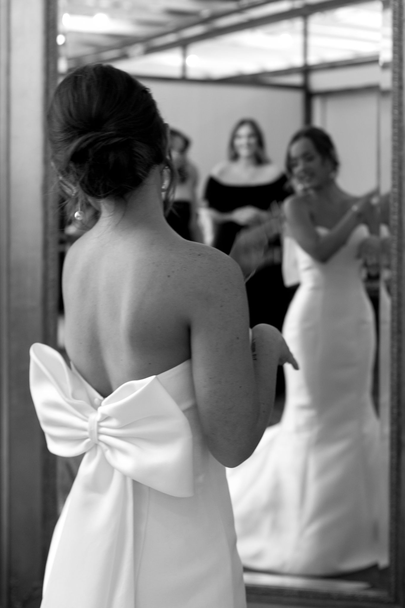 A woman lovingly helps a bride into her wedding dress, symbolizing friendship and the beauty of shared moments before th