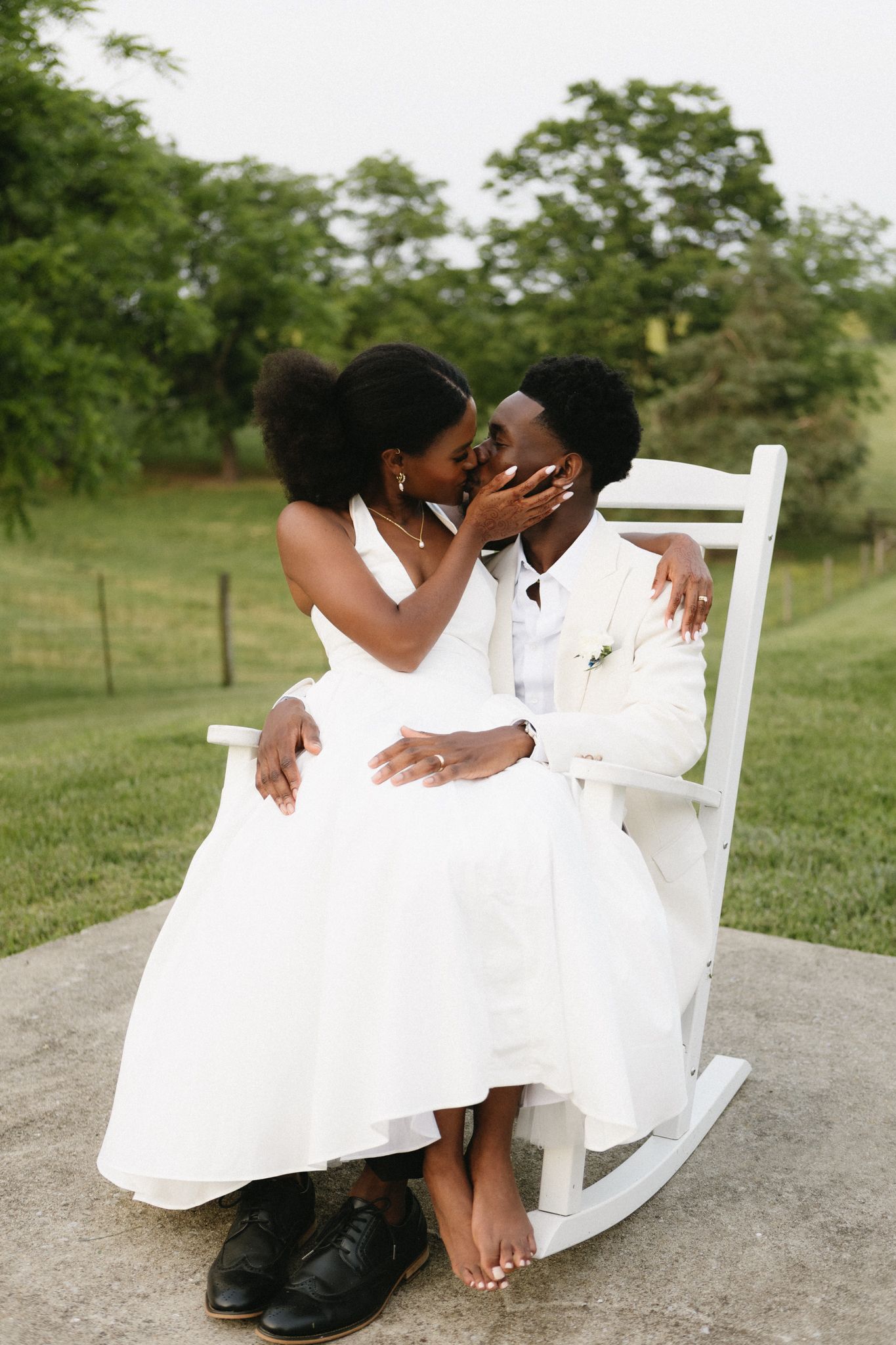 Intimate wedding couple shares tender moments in a garden setting on a white rocking chair.