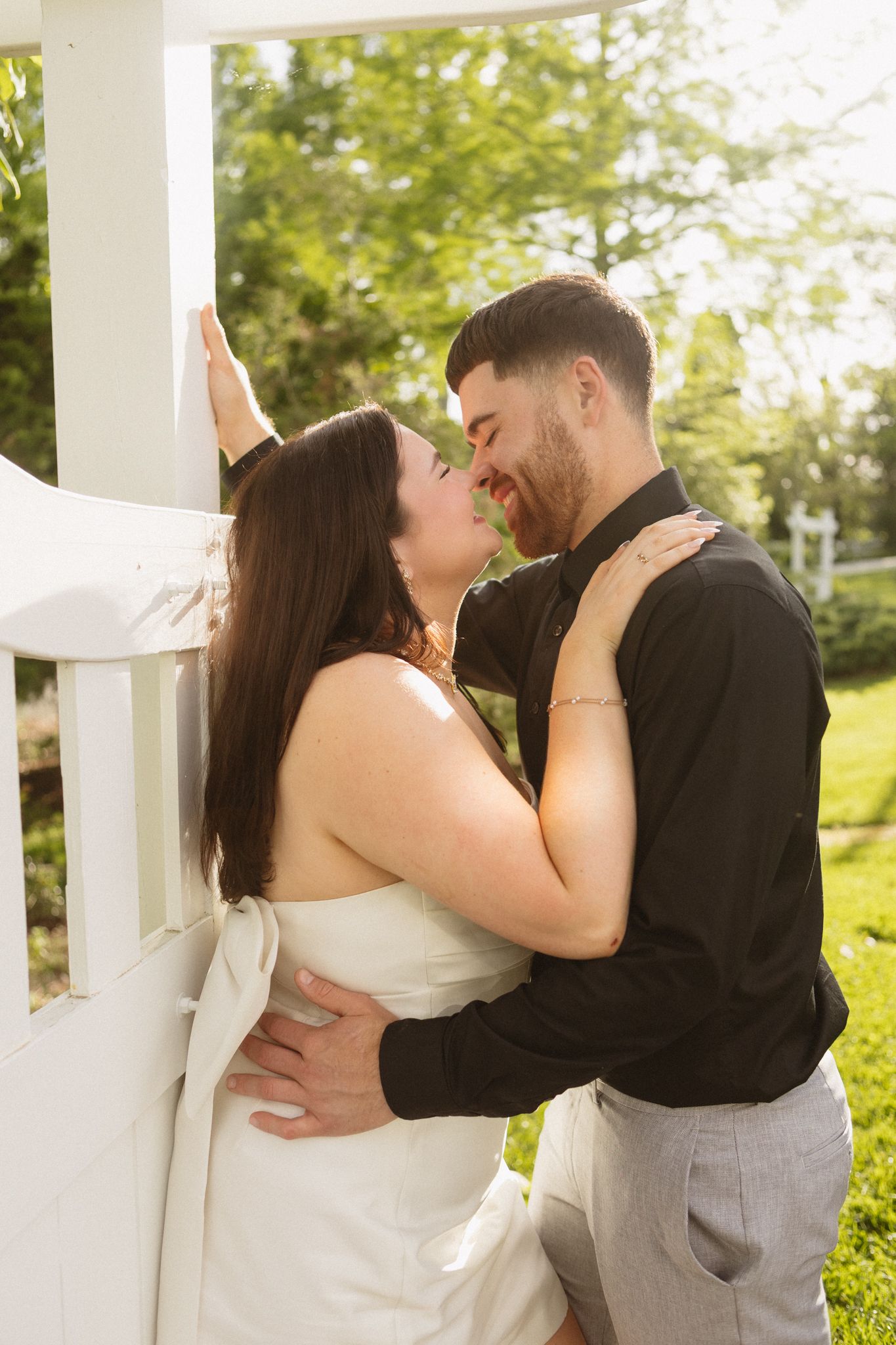 A tender embrace between a couple against a white column backdrop with natural lighting.
