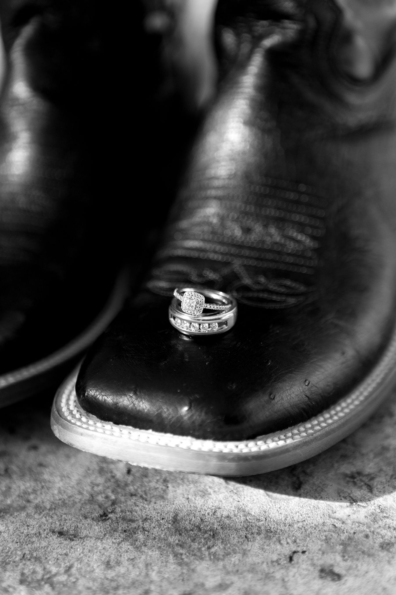 Black and white detail shot of western boots showing intricate leather stitching and design.