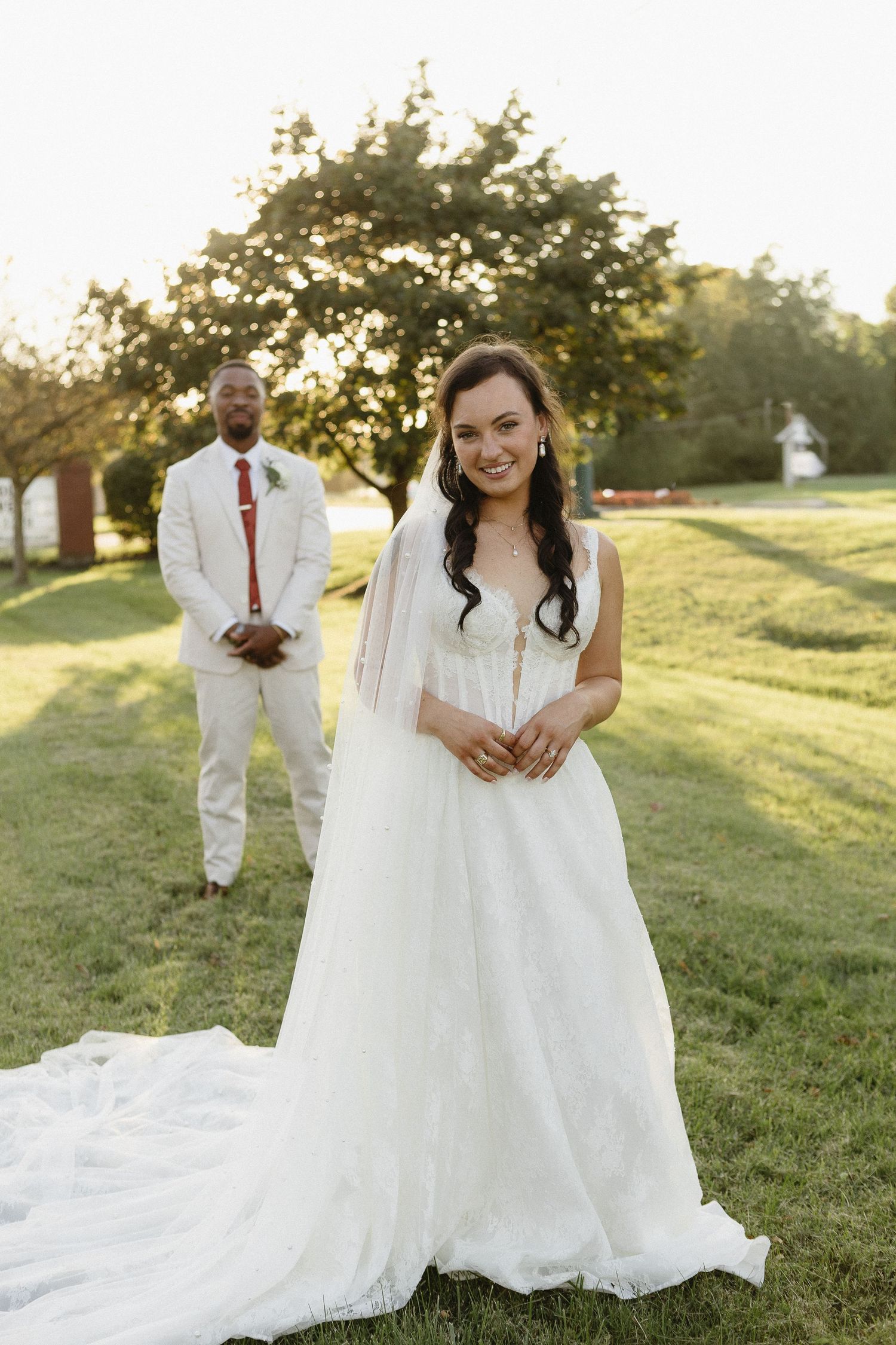 Newlyweds walking and embracing on a grassy hill during golden hour.