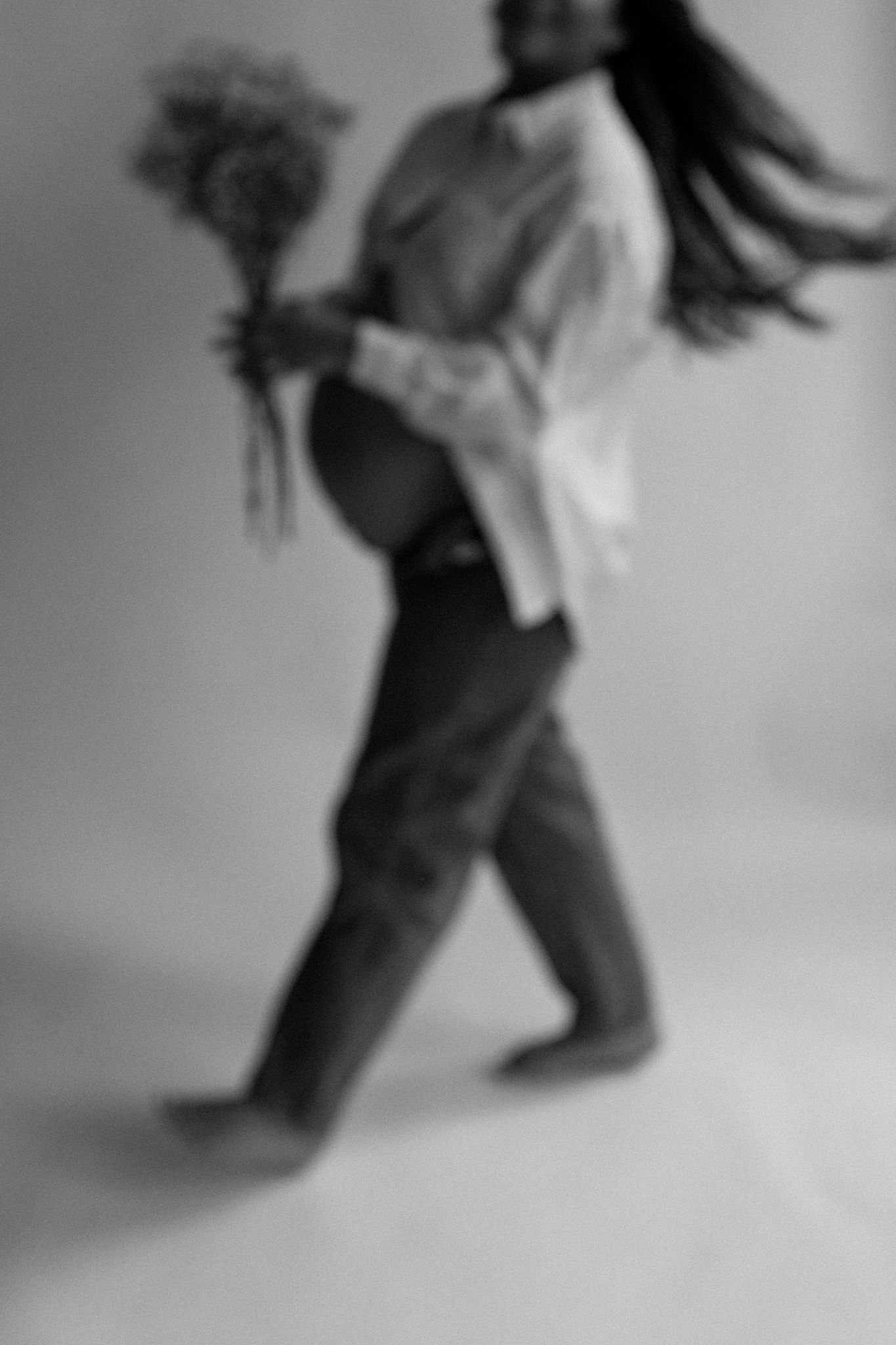 Indoor maternity photoshoot in a cozy studio setting. A pregnant woman in an elegant dress poses gracefully, highlightin