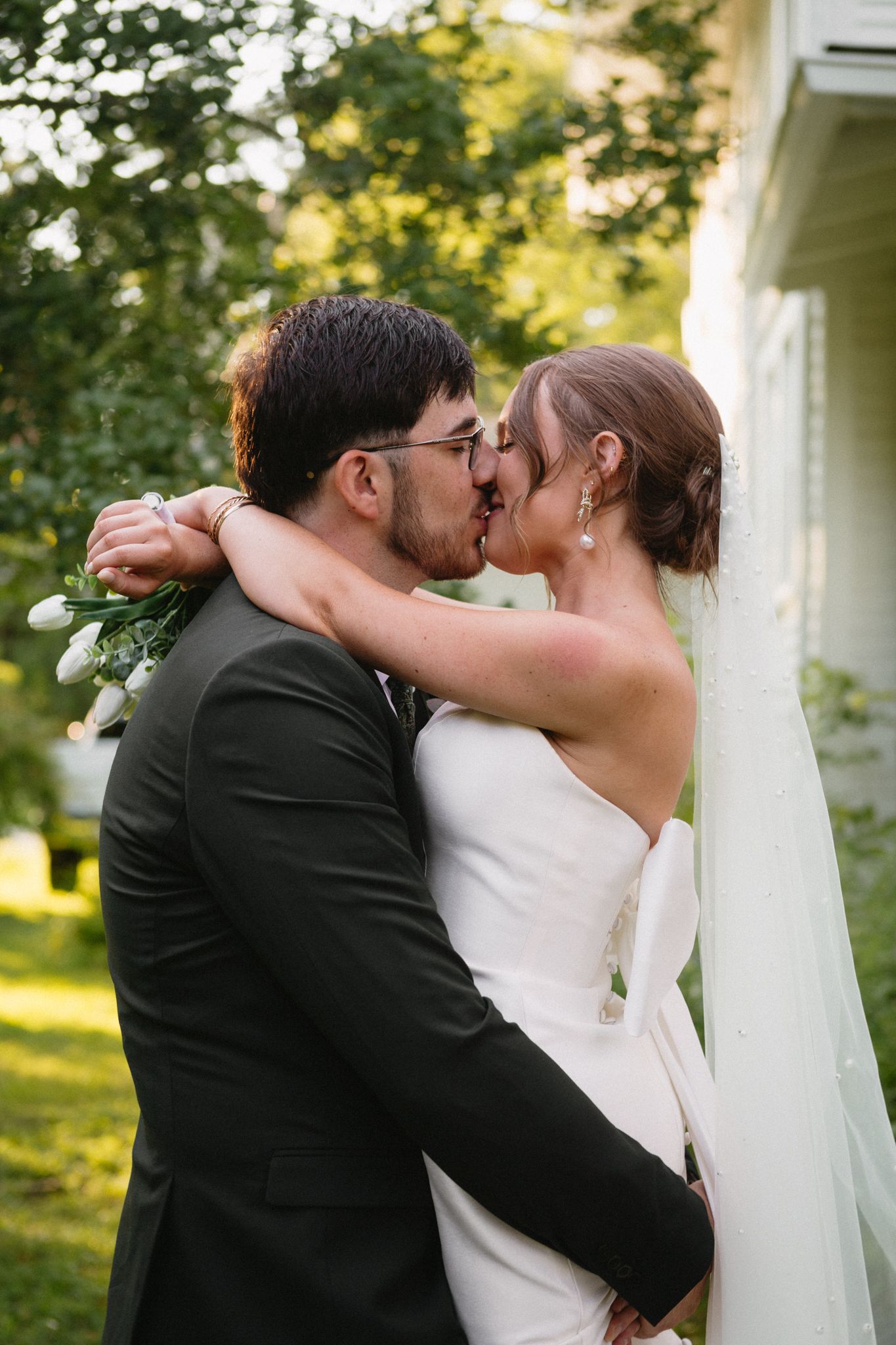 Bride and groom sharing a tender moment in a sunlit grassy field