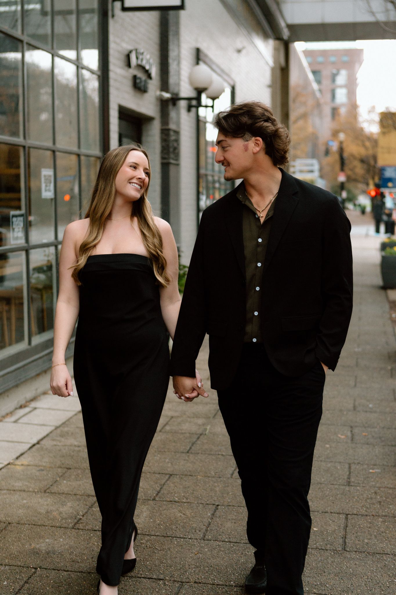 engaged couple walking holding hands, sharing an intimate moment in downtown Louisville