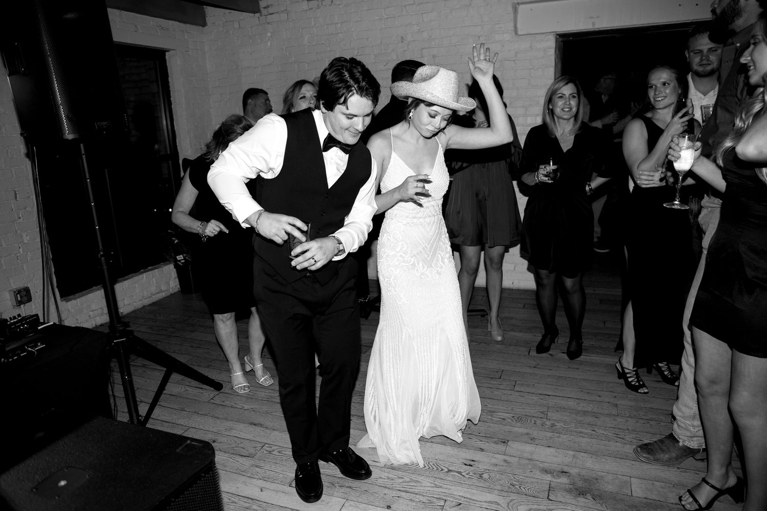 A lively dance moment at a wedding reception as guests watch the couple on the wooden dance floor.
