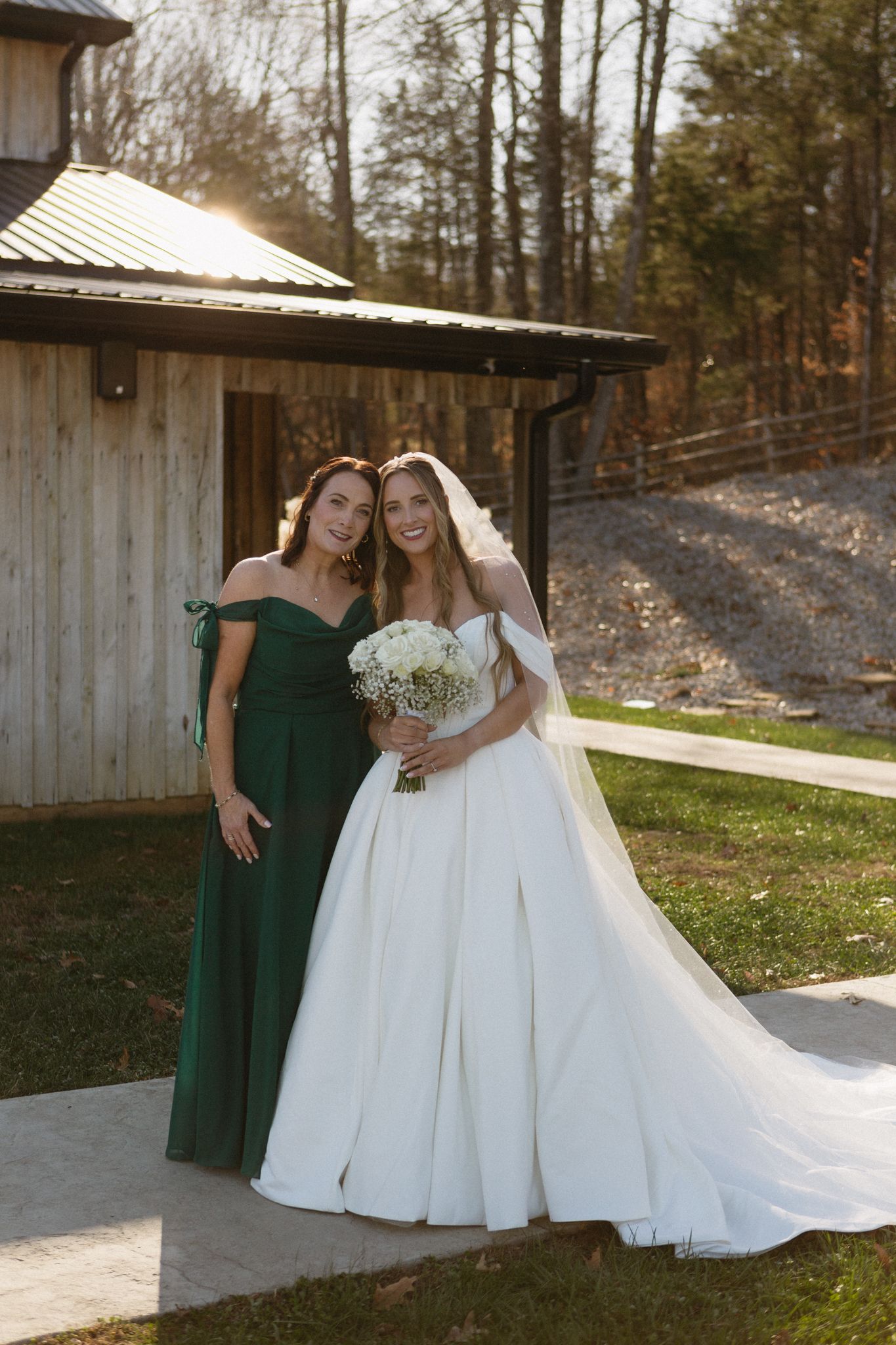 A wedding photo showing two elegant dresses - an emerald green bridesmaid gown and a flowing white bridal gown with train.