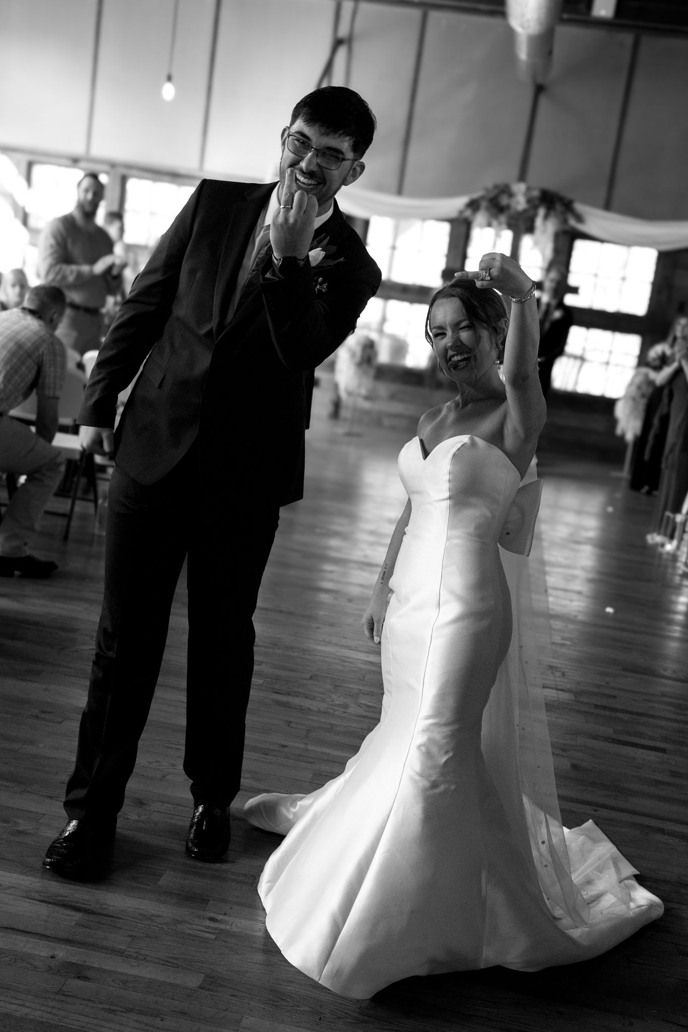 bride and groom walking down the aisle showing new wedding rings and smiling black and white photo