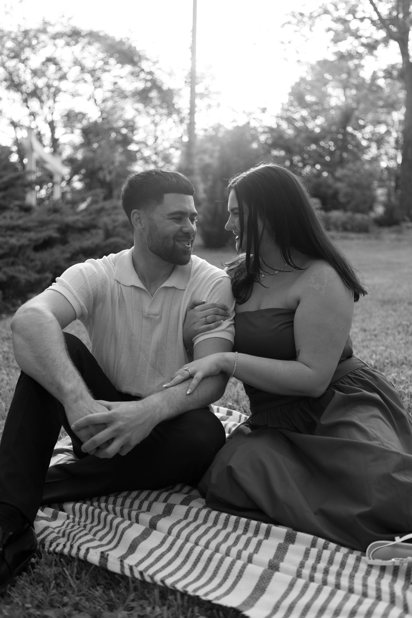 Black and white photo series of couple relaxing on striped blanket in outdoor setting.