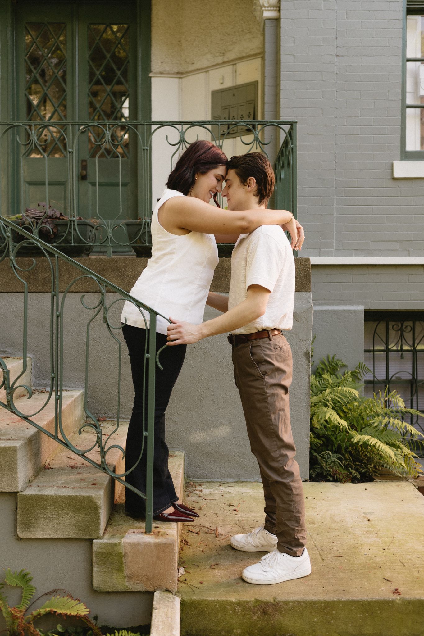 A romantic couple shares tender moments in a series of connected photos on a stone porch with decorative railings.
