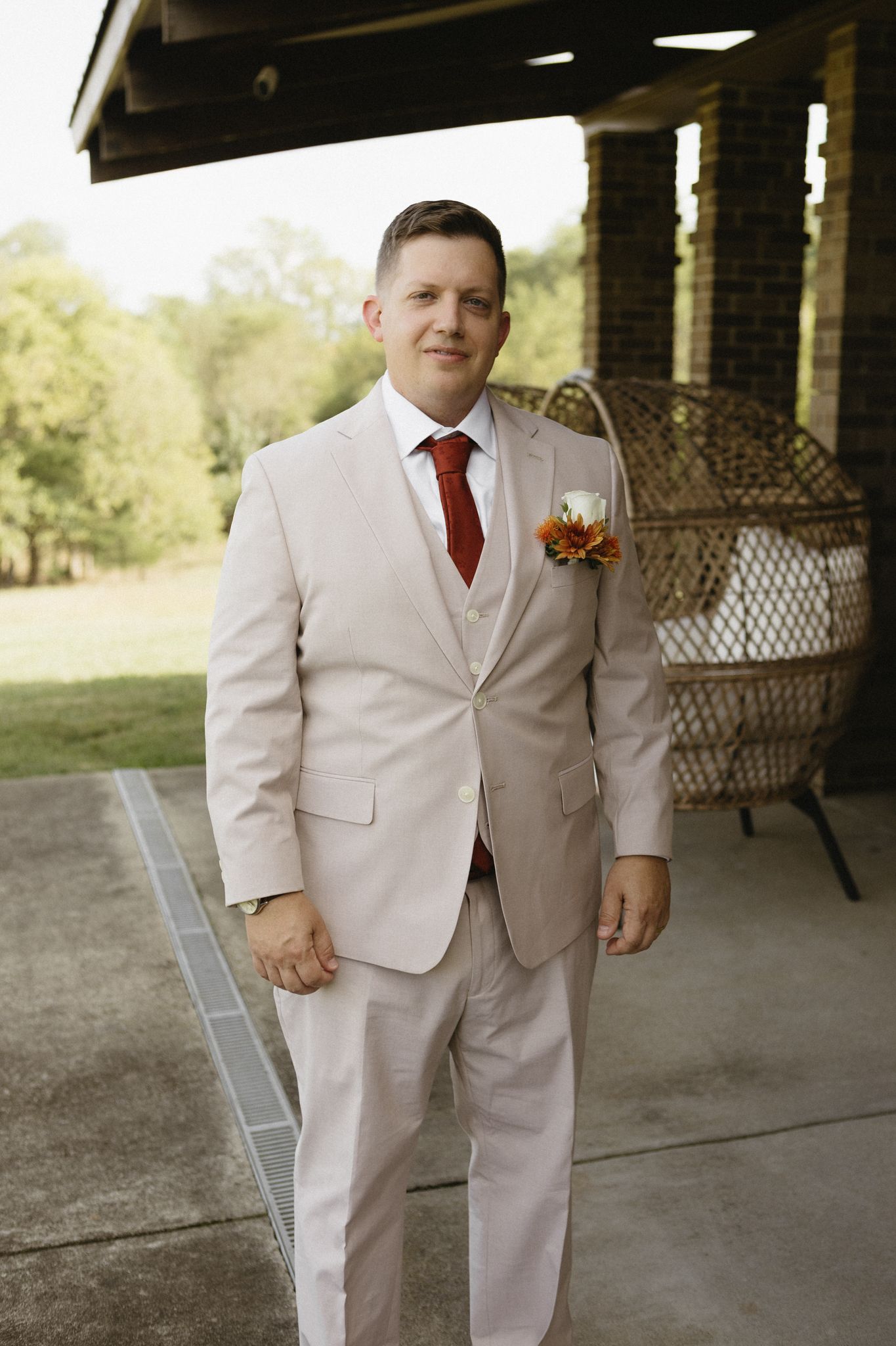 Wedding party members in cream-colored suits stand together in a covered outdoor venue.
